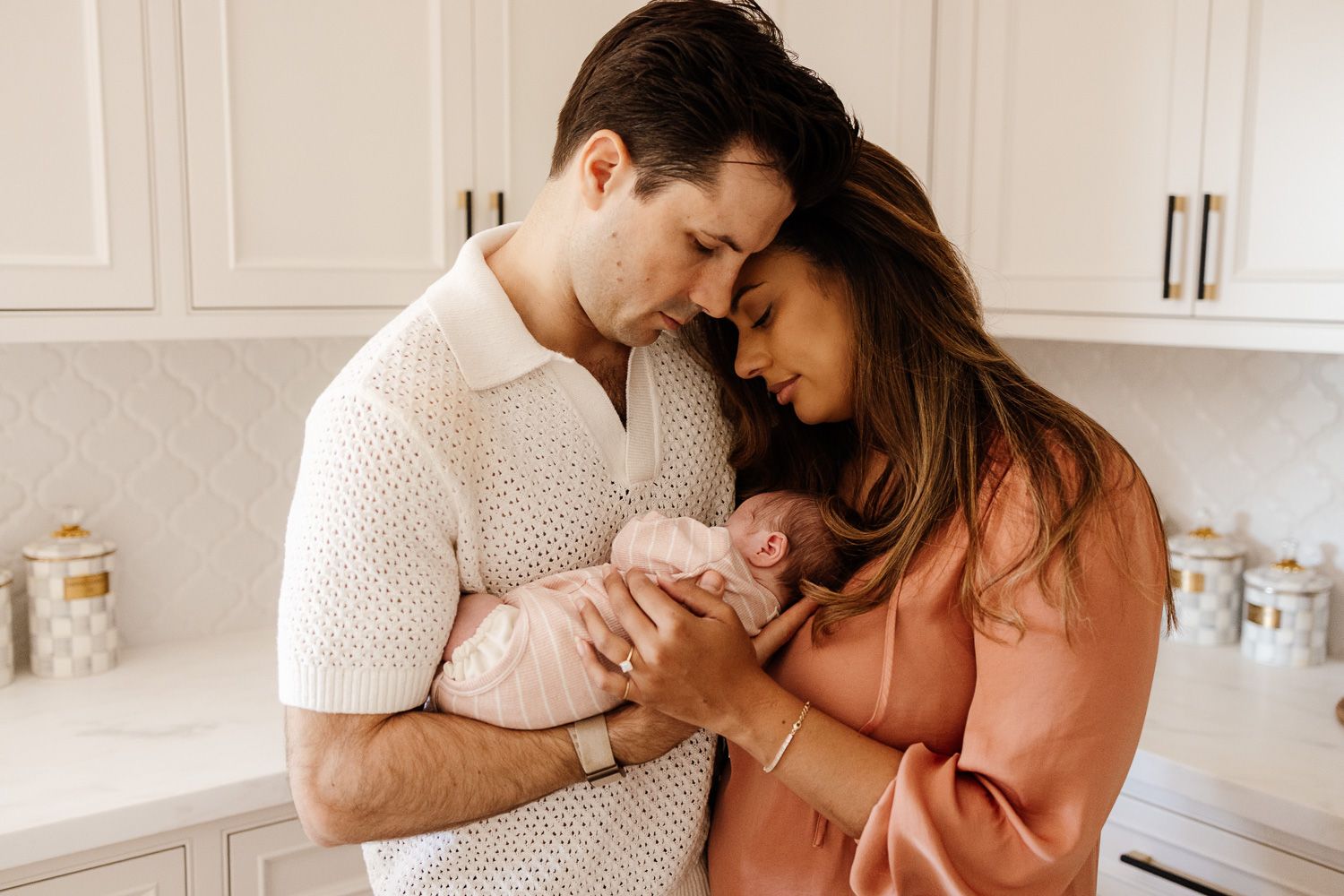 parents cuddle their newborn baby in their kitchen in Los Gatos at their in-home newborn photoshoot