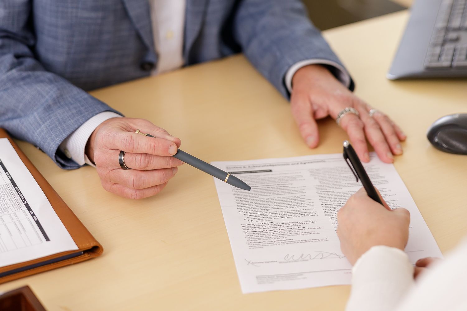 man real estate agent using pen to point at contract paper that woman hand is signing for lifestyle branding photoshoot in Seattle WA office