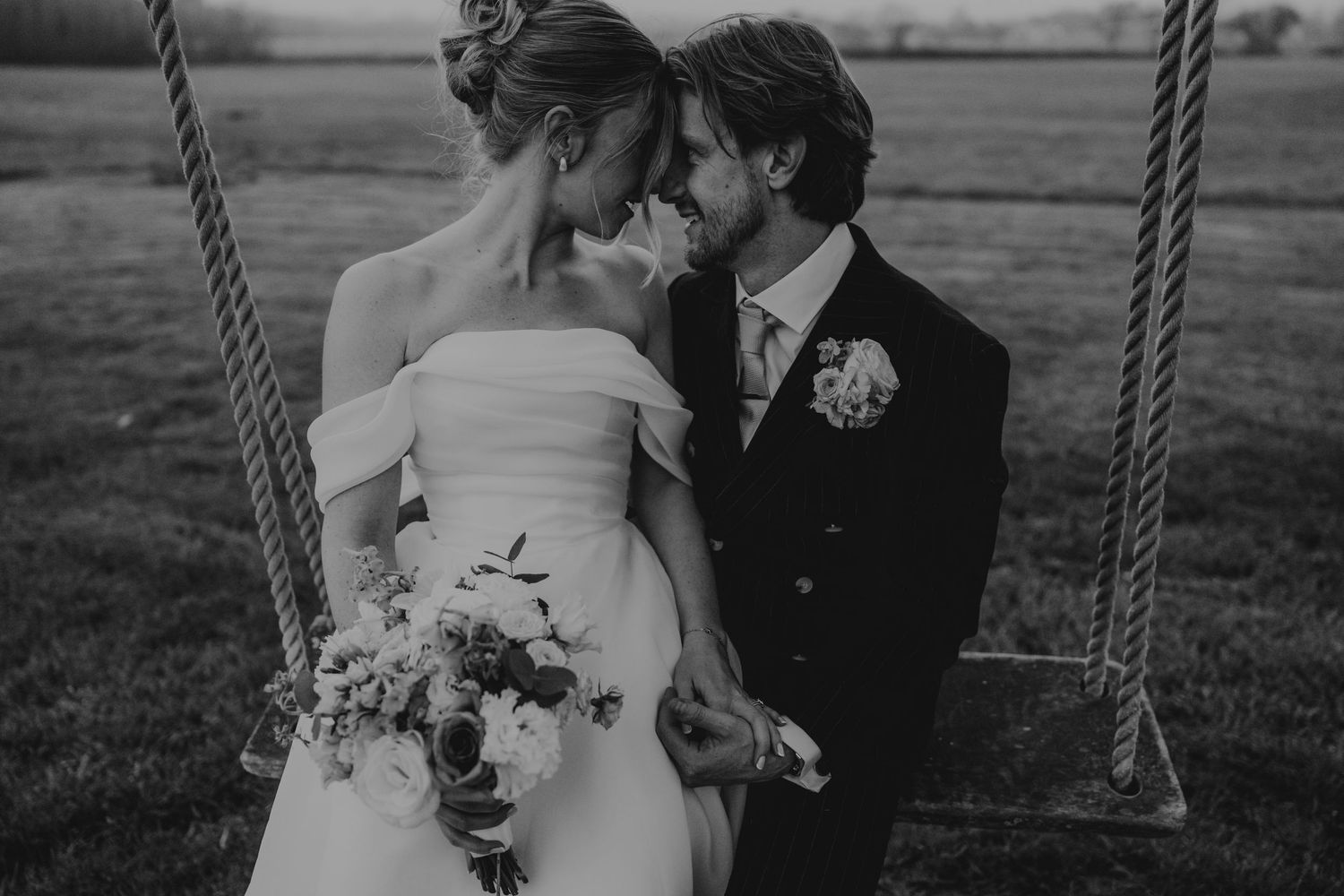 bride and groom sitting on the swing in the grounds at Quantock Lakes