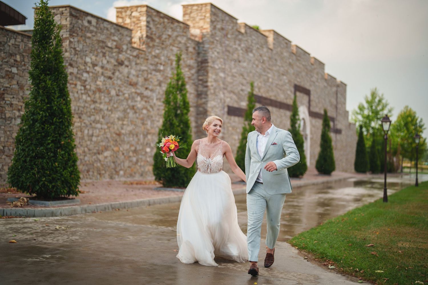 Joyful wedding guests and newlyweds celebrate with raised arms during an outdoor reception ceremony.