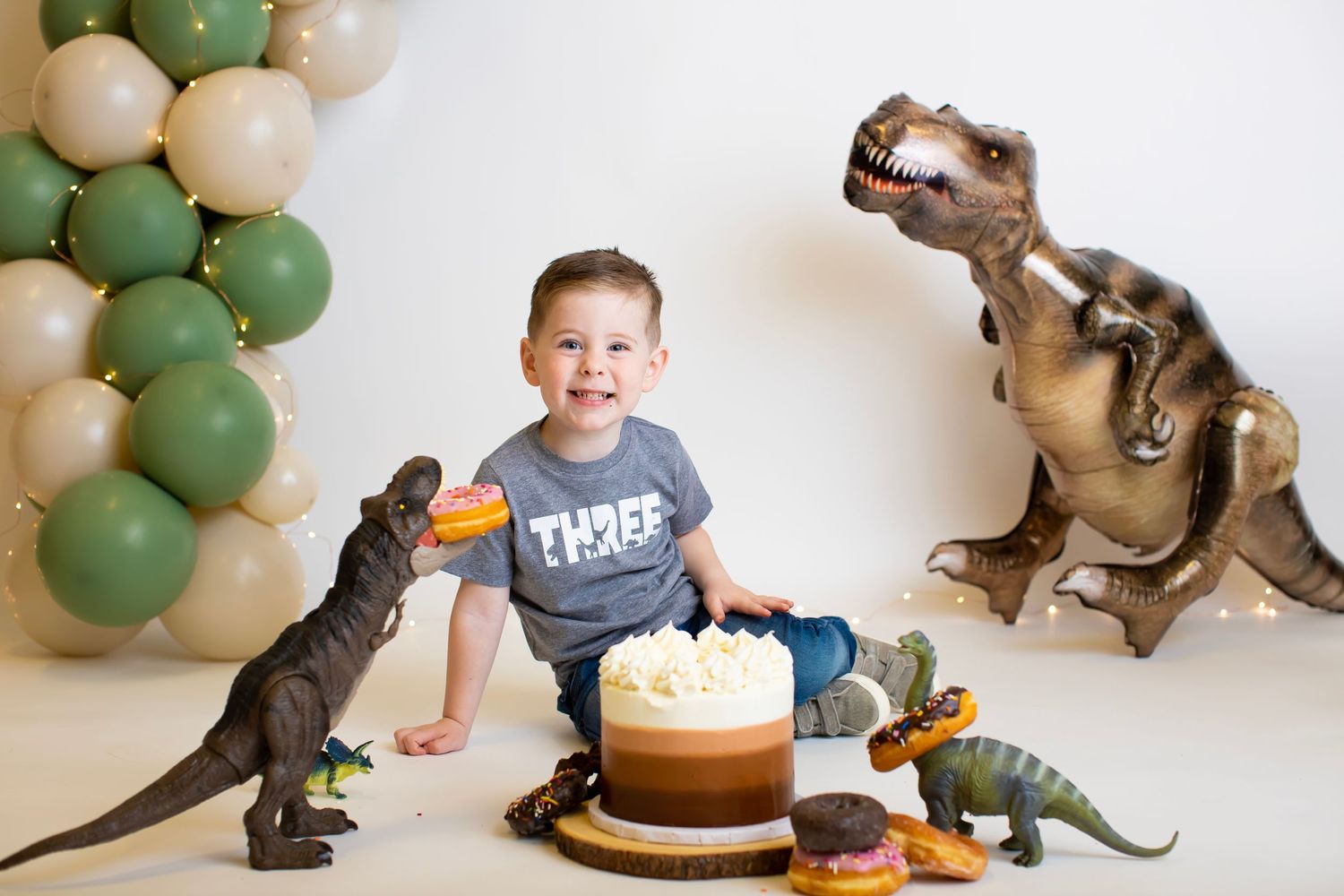 Birthday celebration with dinosaur theme featuring cake and balloon decorations.