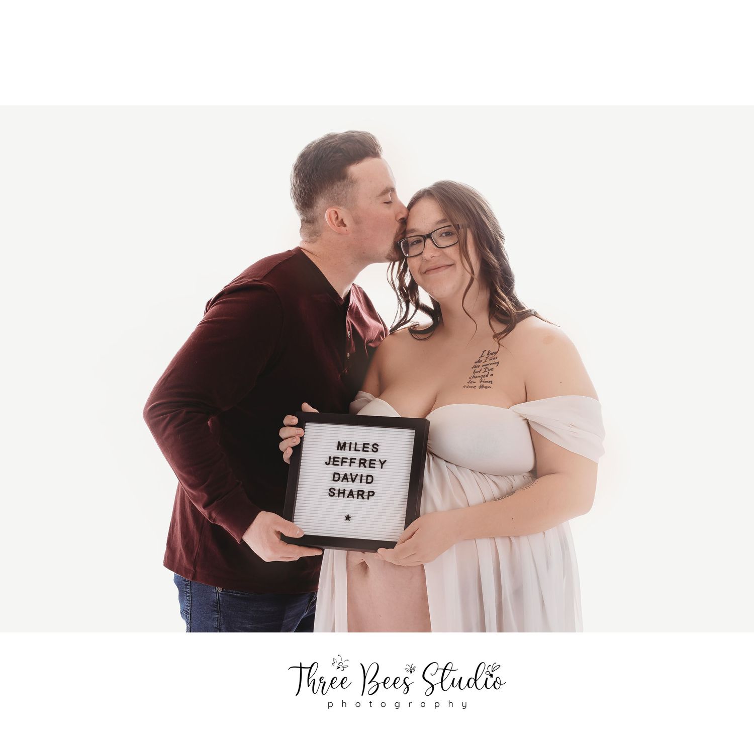 Couple poses with sign in romantic maternity photo.
