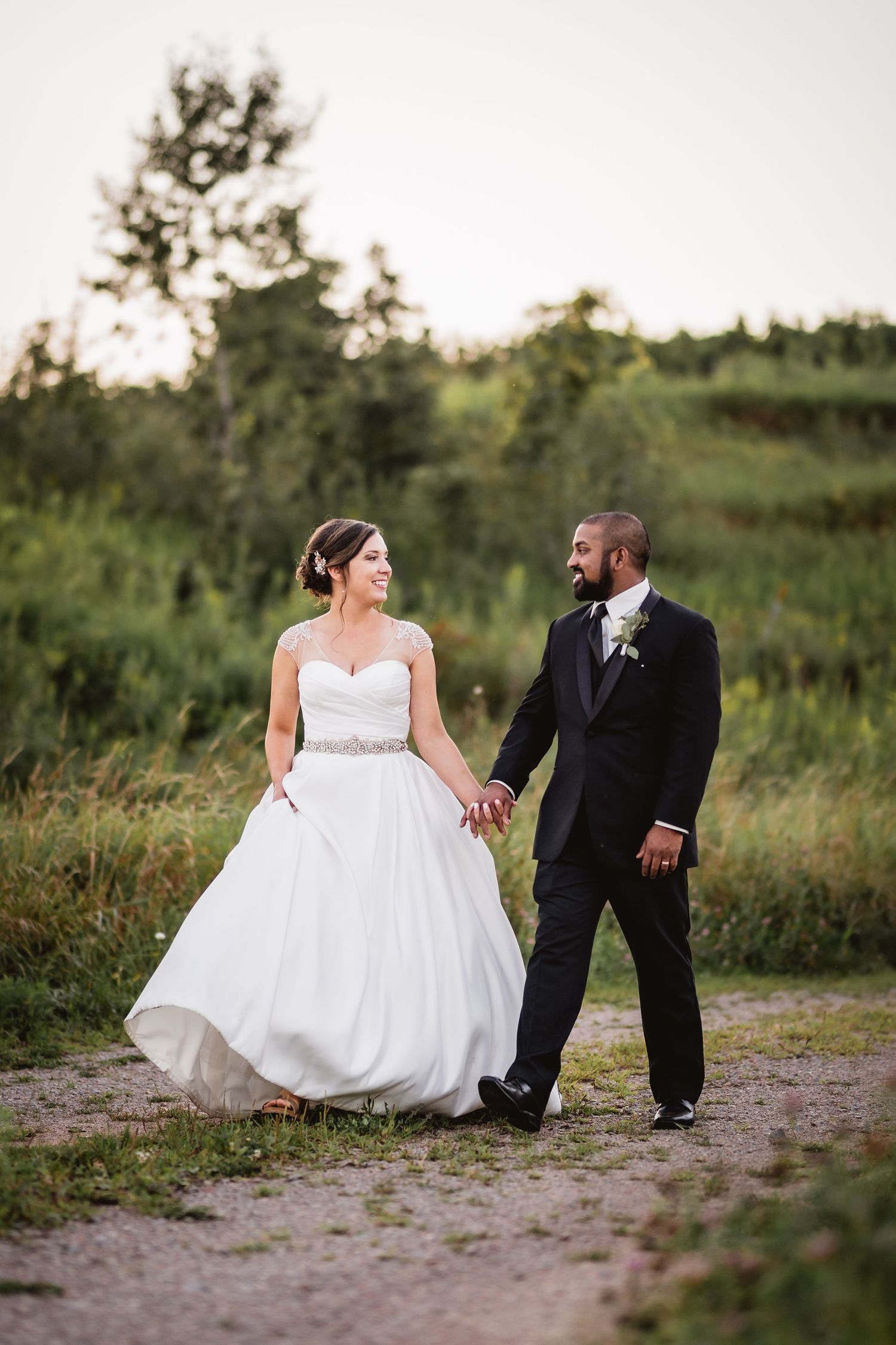 Jon + Natalie holding hands and walking at sunset on their wedding day.