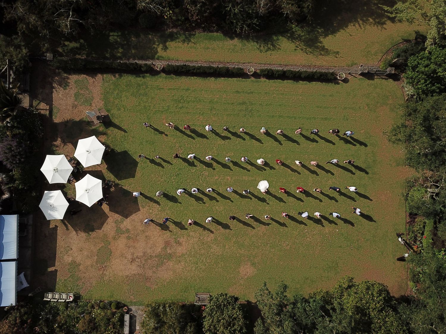 drone shot of wedding guests spend out two meters apart on the lawn of the reception venue