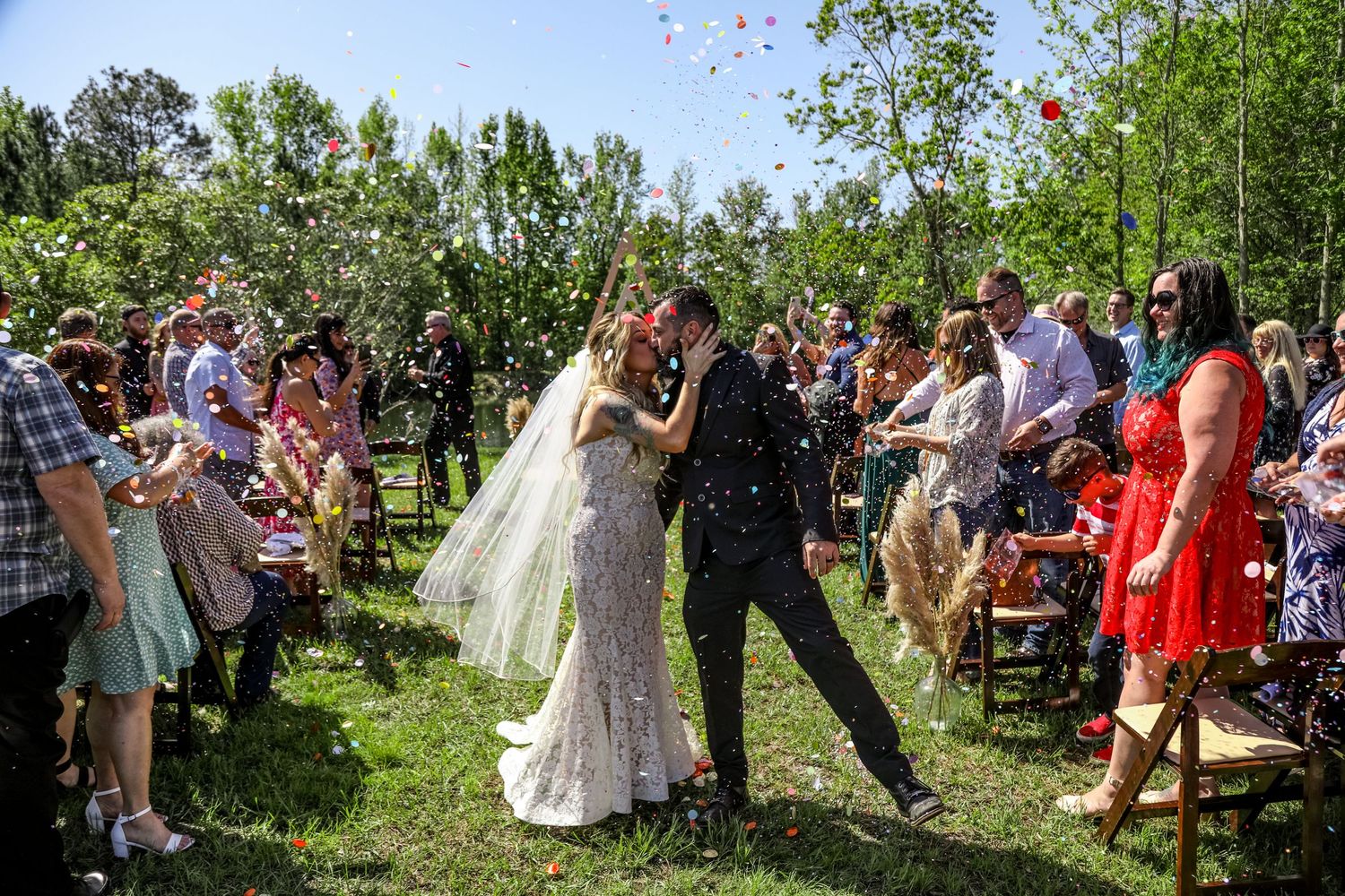 Wedding guests throw flower petals during an outdoor garden celebration.