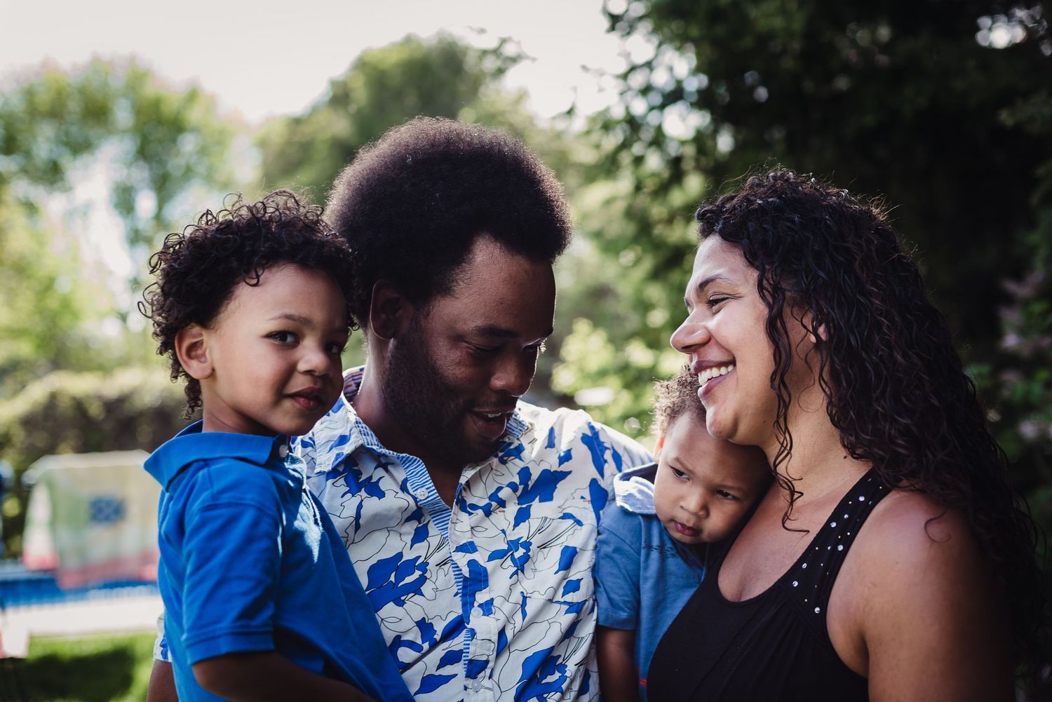 Afternoon sun backlights a colour image of a black family holding one another.
