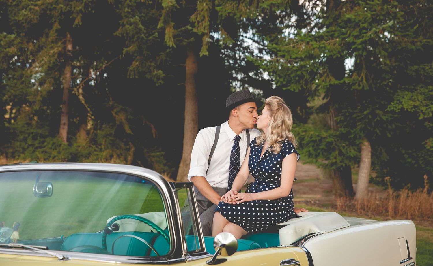 50s themed photo shoot of couple sitting on back of retro convertible car
