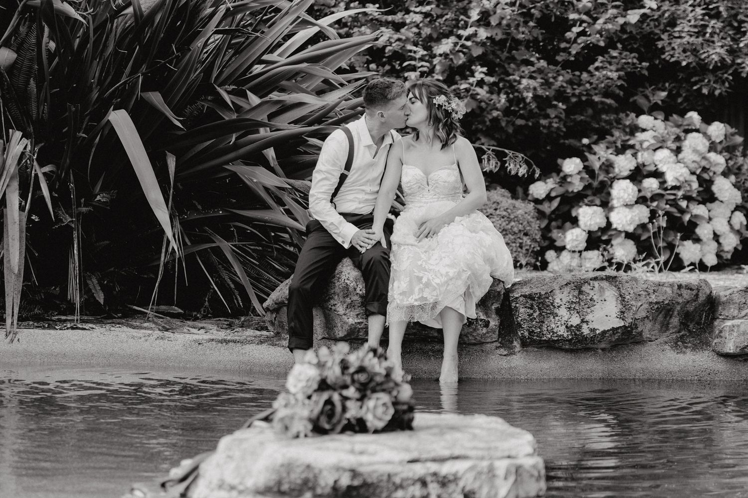 Vintage-style black and white photo of couple sitting by garden pond.