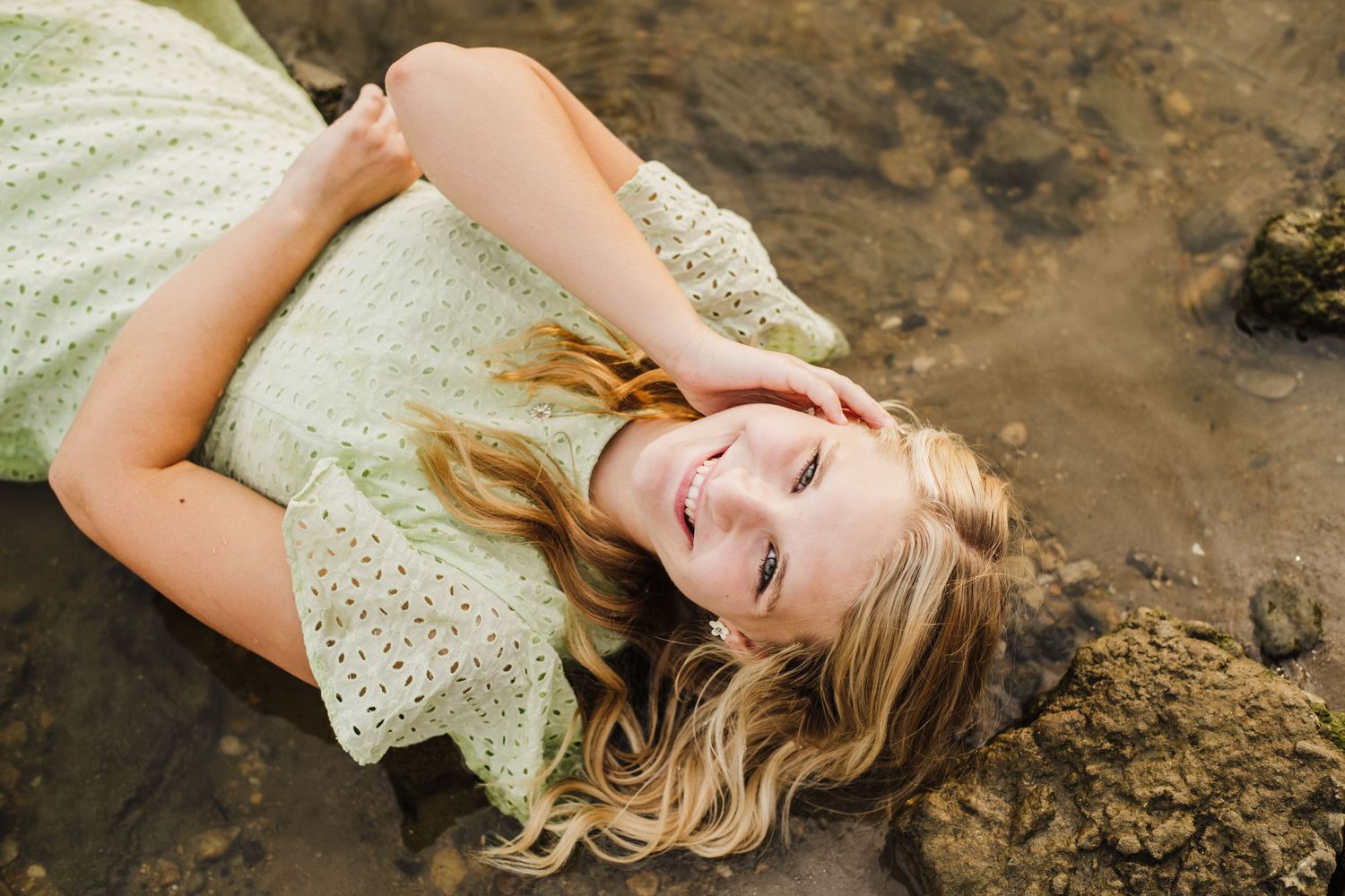 Artistic portrait series showing someone lying on muddy ground in a white lace dress with dramatic lighting.