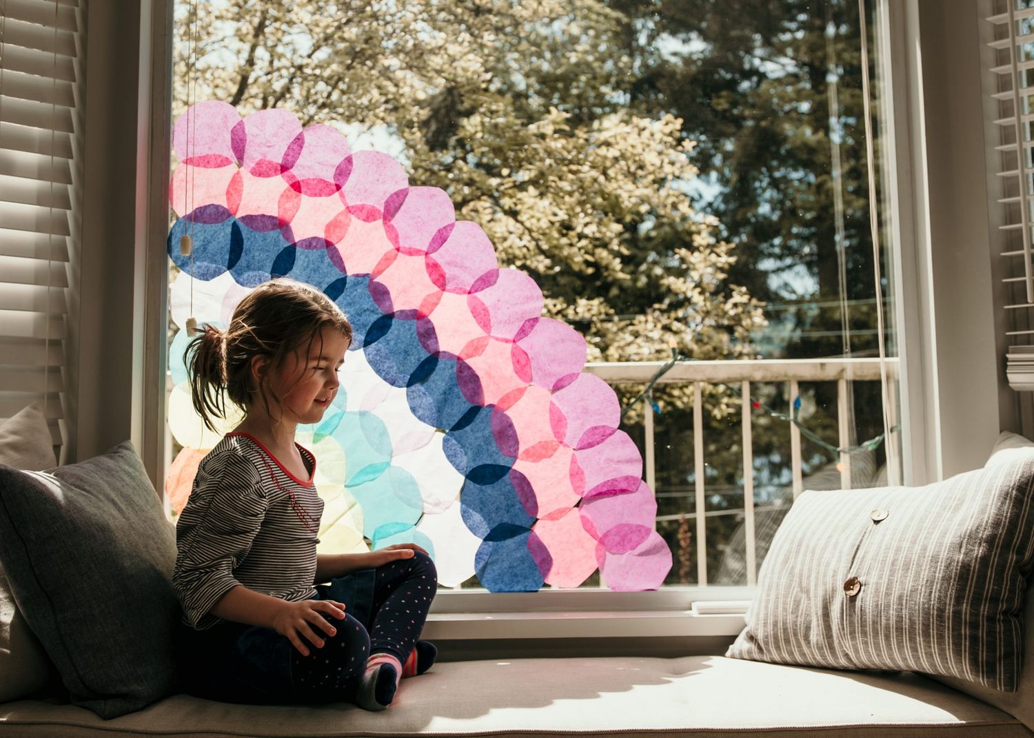 Colorful balloon arch installation by window creating rainbow effect.