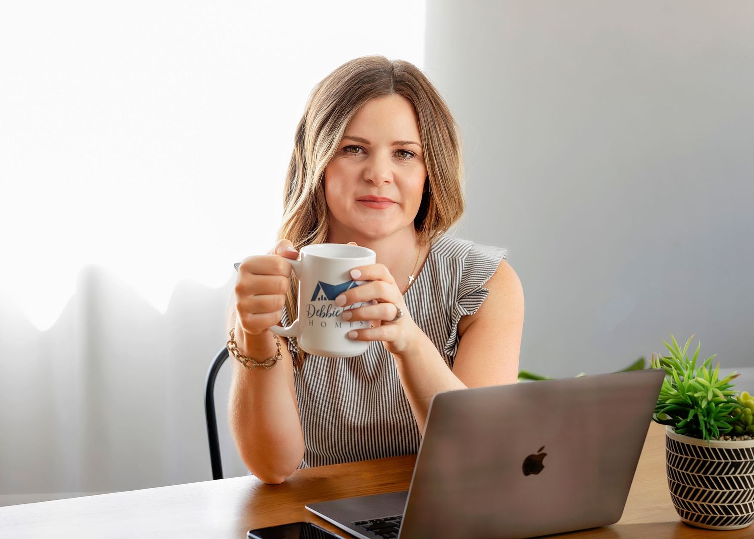 Professional working at desk with laptop and coffee mug in modern home office setting.
