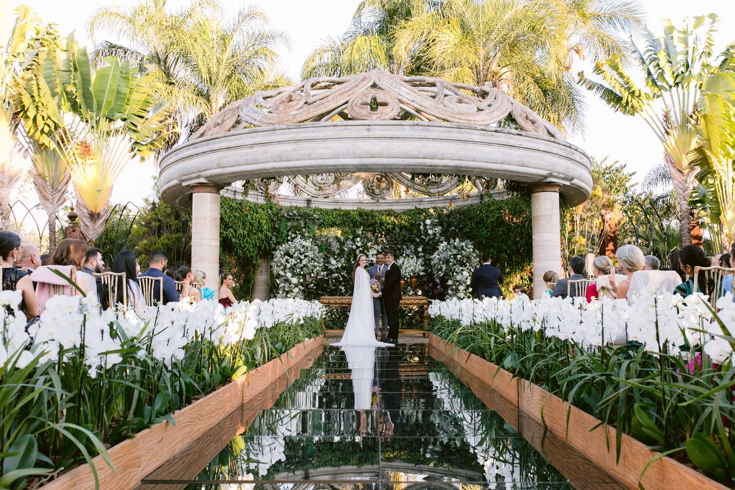 An elegant outdoor wedding ceremony setup with a gazebo and floral decorations.