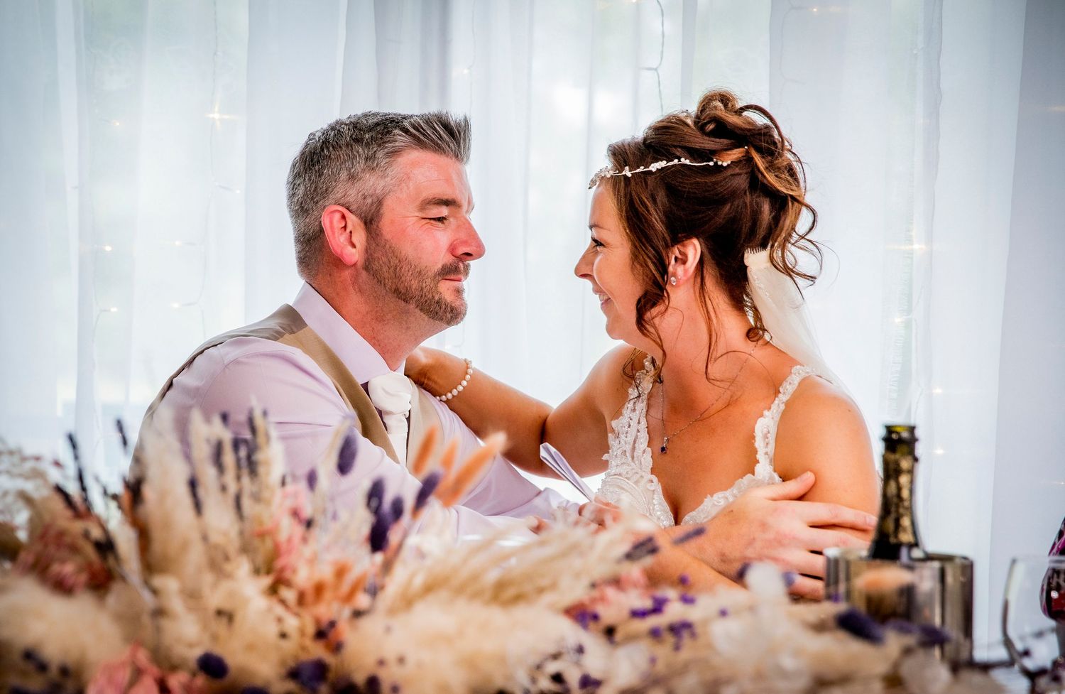 Intimate wedding reception scene with white draping and soft lighting.