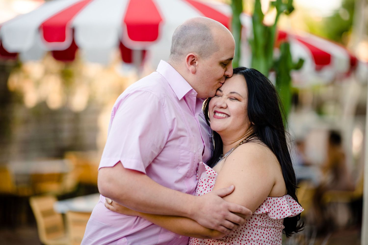 A couple embraces and laughs under a red and white striped carnival tent.