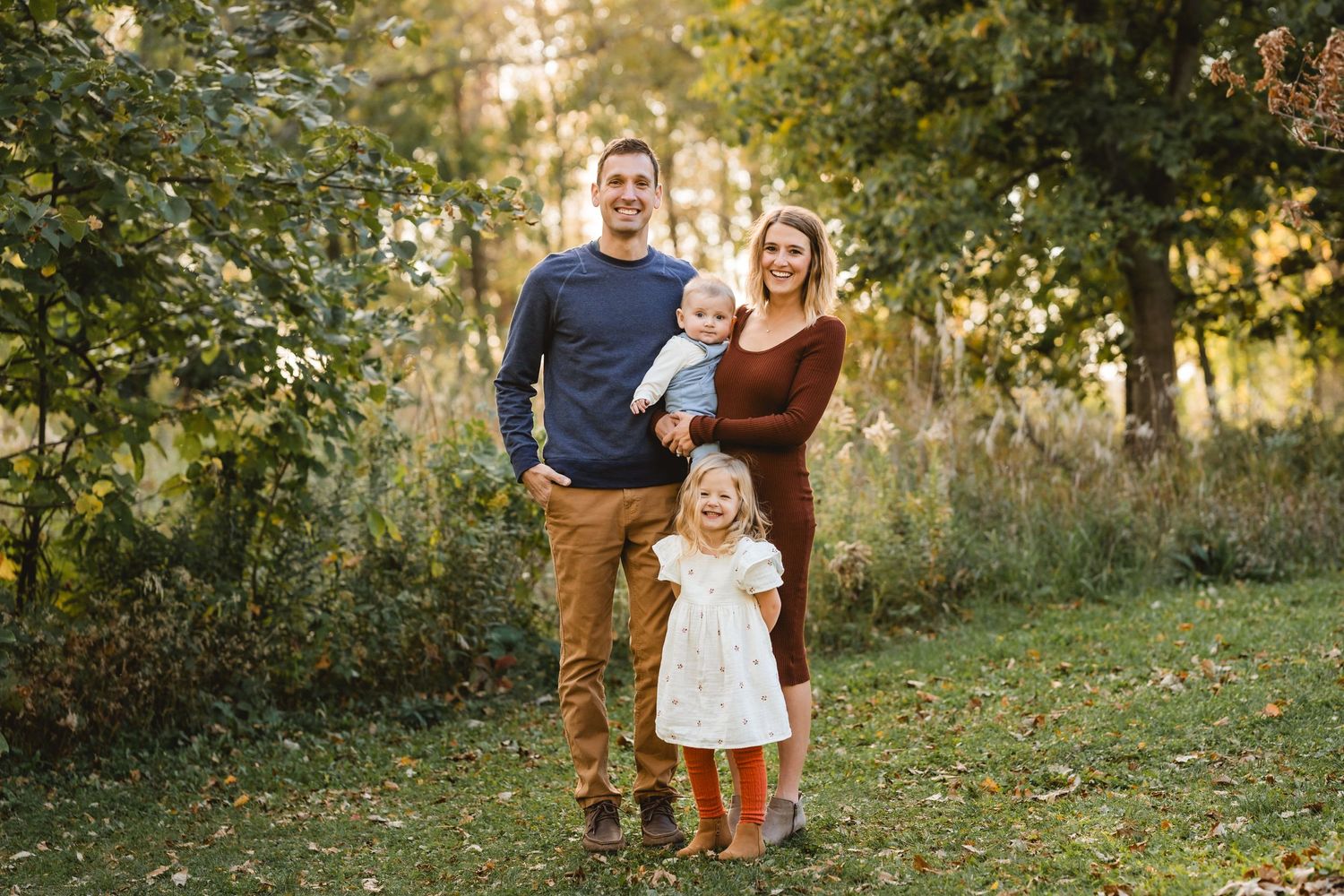 A family of four, standing and smiling
