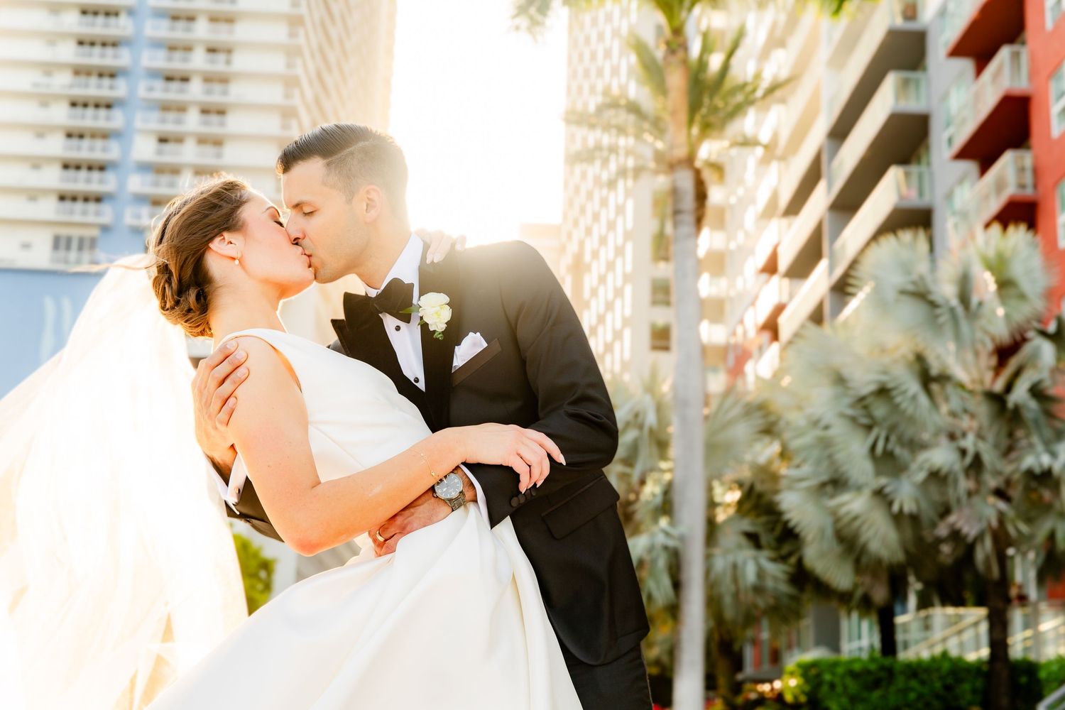 Romantic beach wedding photos at sunset with palm trees in background.