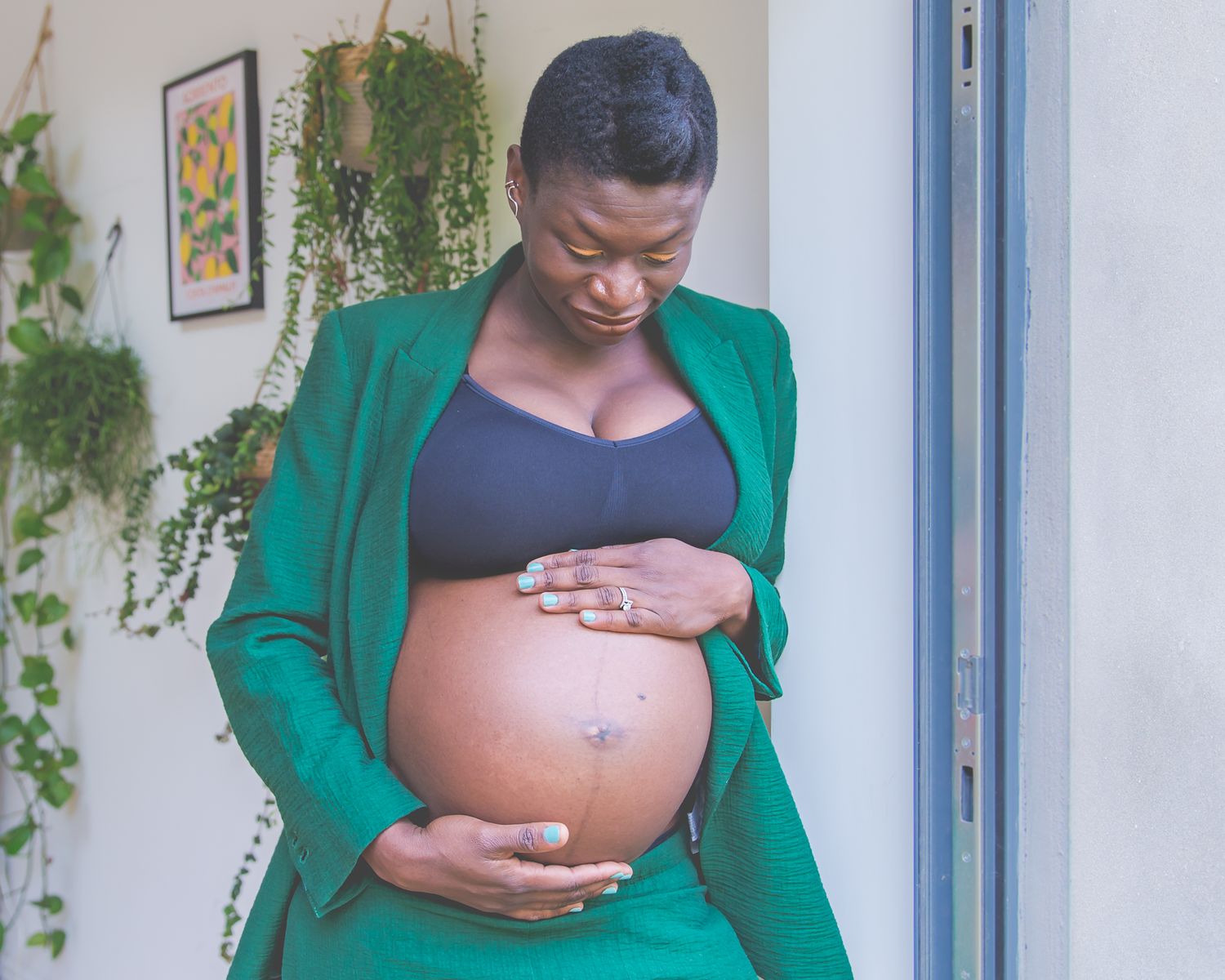 A pregnant mother holds her baby bump during an in-home maternity photoshoot in Bristol