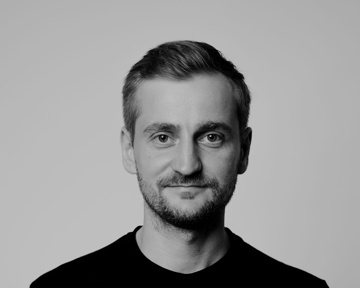 Professional headshot portrait in black and white against a simple gray background.