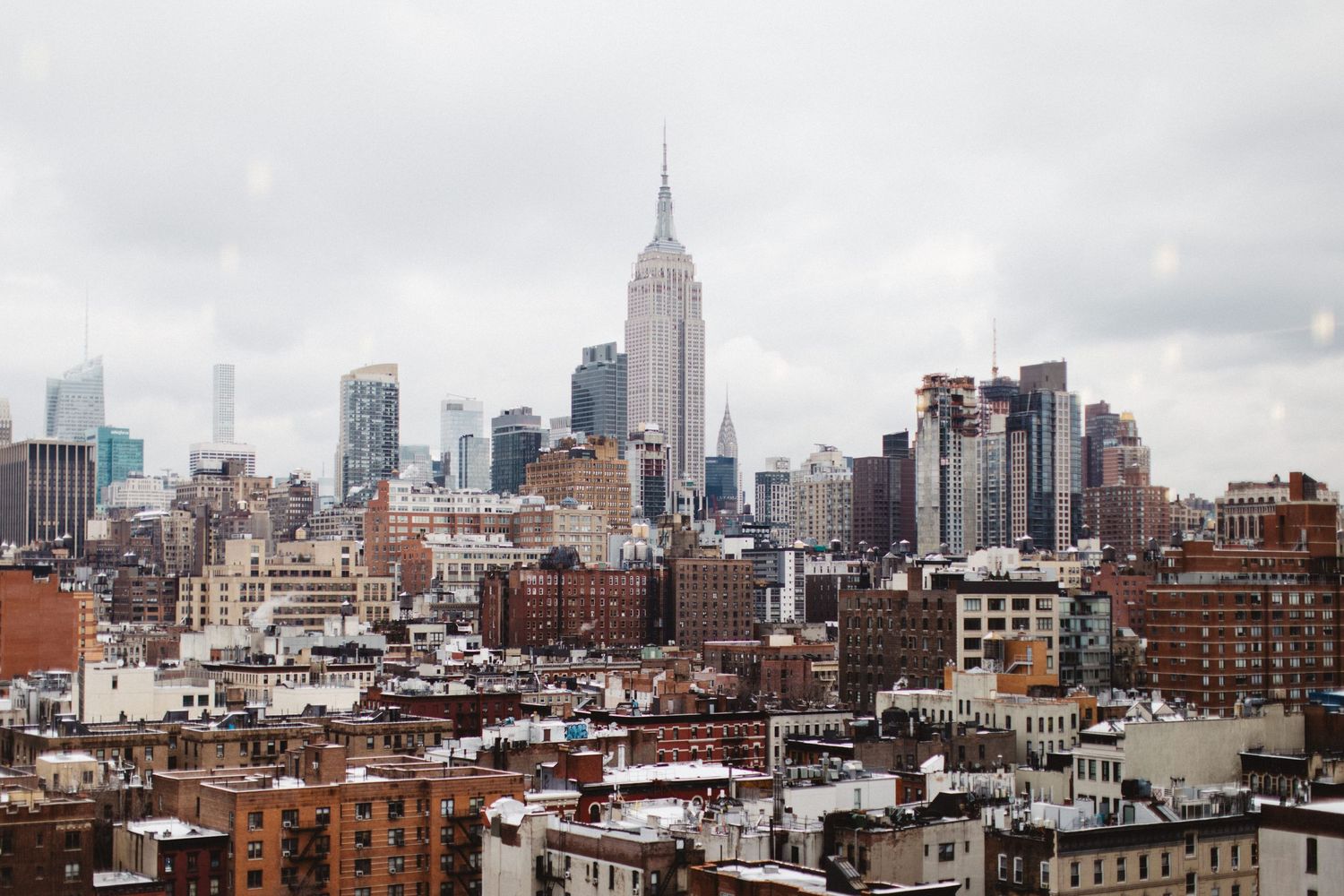 New York City skyline featuring the Empire State Building among modern skyscrapers on a cloudy day.
