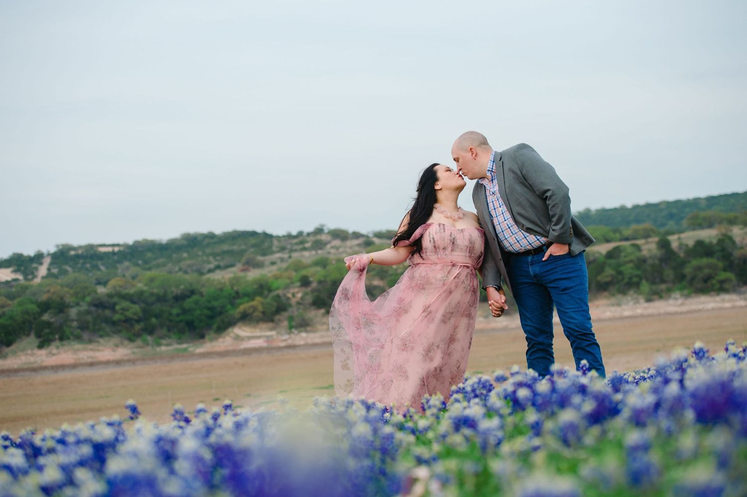Romantic couple sharing a moment in field of Texas bluebonnets during sunset.