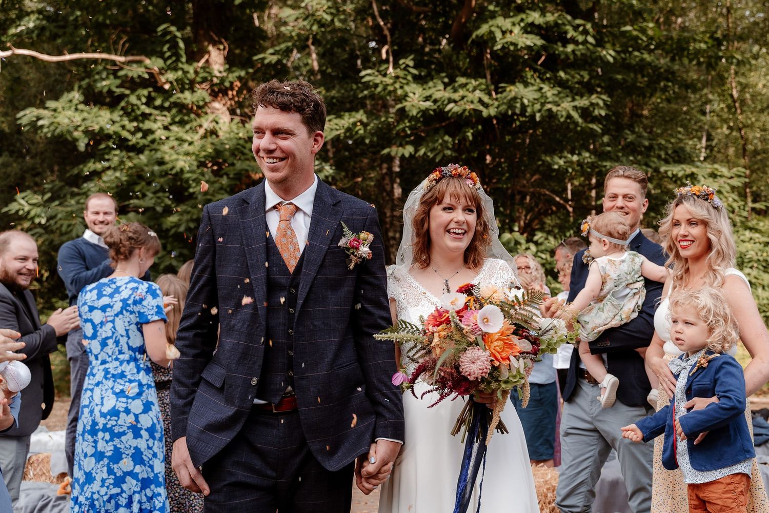 A newlywed couple walk through their confetti tunnel