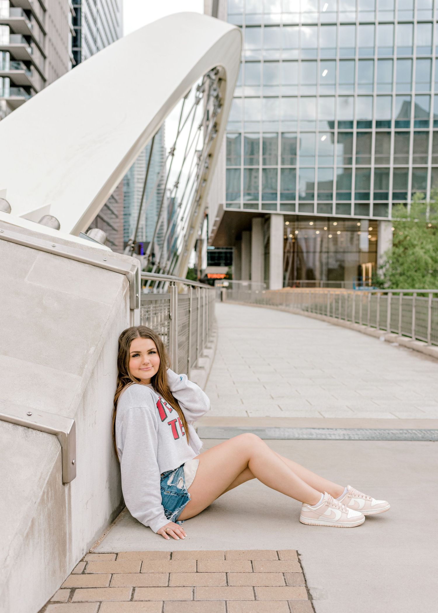 Street style portrait showcasing casual wear against modern urban architecture and glass buildings.