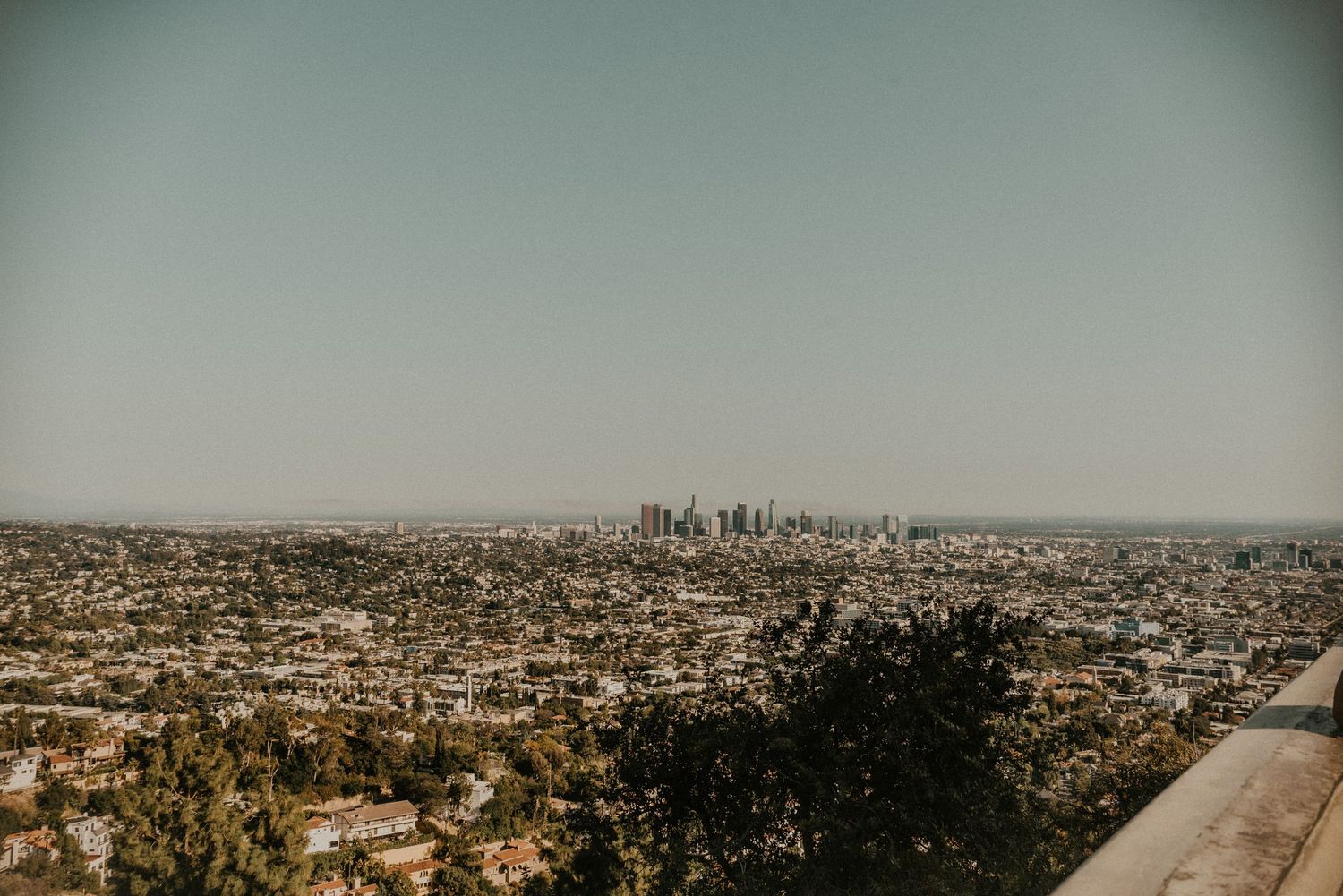 Los Angeles skyline view with downtown skyscrapers visible in the distance on a hazy day.