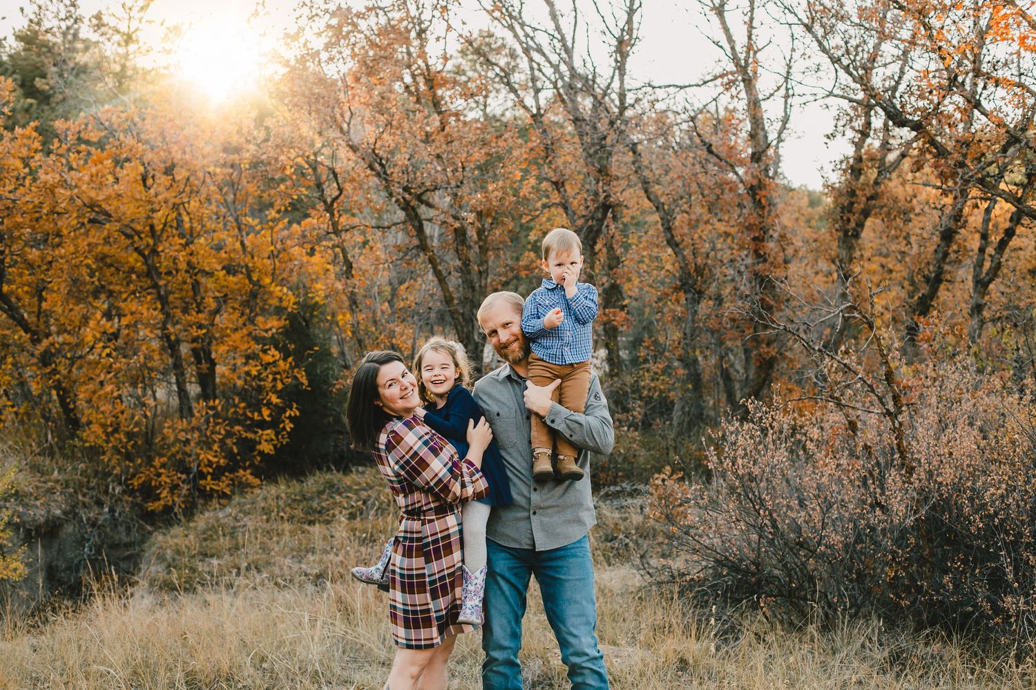Family enjoying sunset moment among golden fall trees.