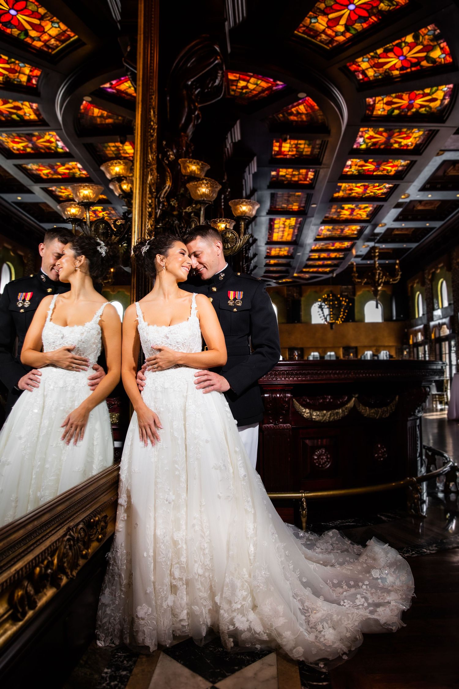 Wedding dresses displayed in an ornate venue with decorative stained glass ceiling details.