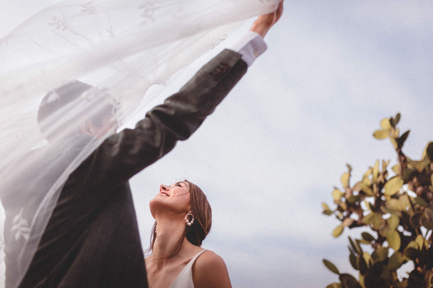 Artistic series of wedding couple portraits against cloudy sky.