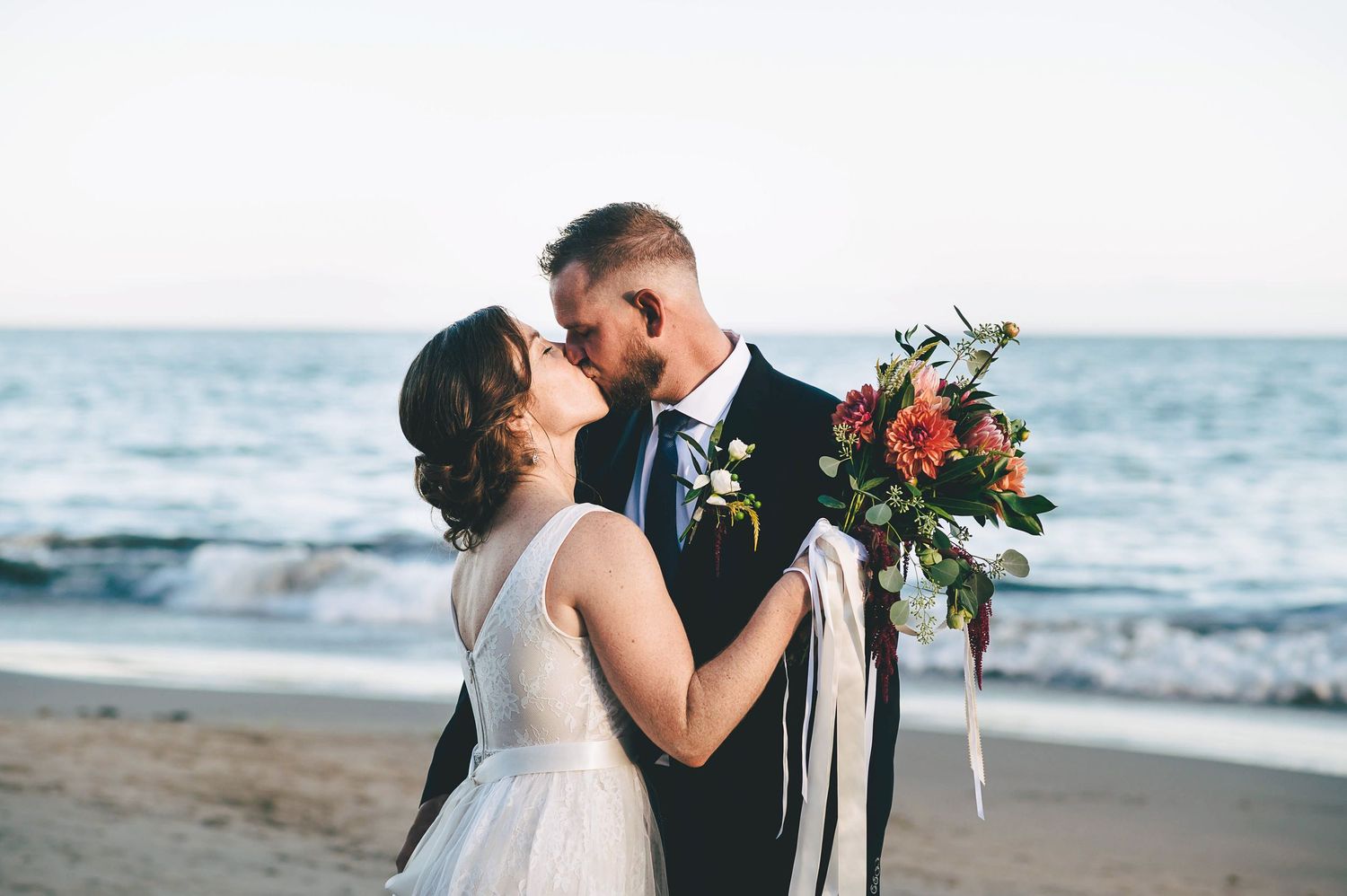 Bride and Broom kissing in front of the ocean on New Brighton beach in Santa Cruz.