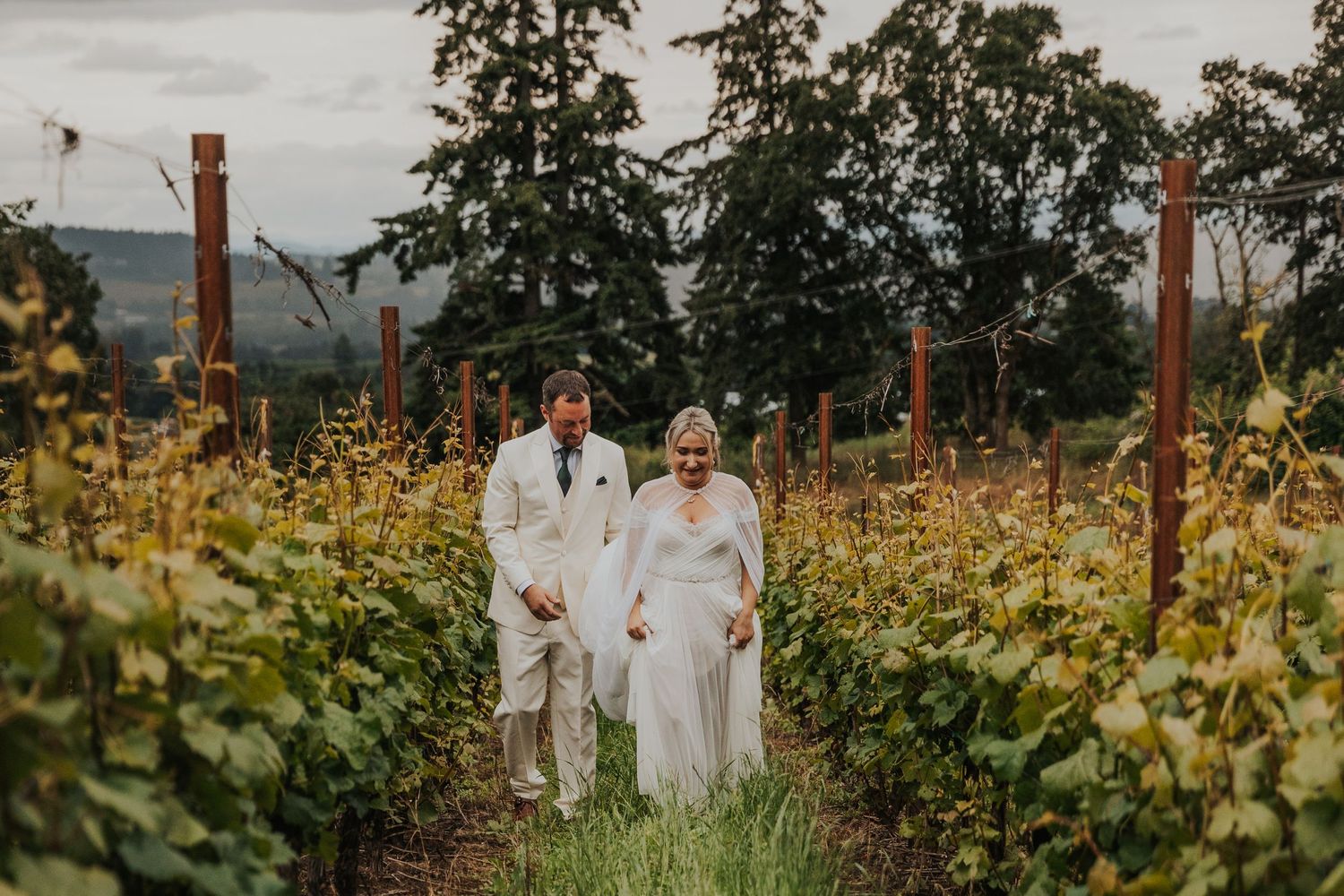 A couple poses in a scenic vineyard setting during golden hour.