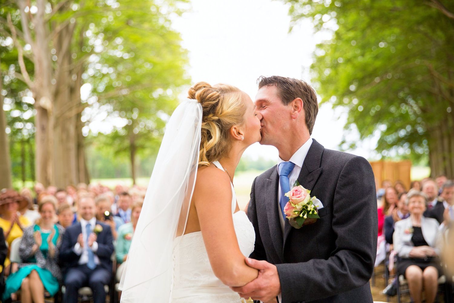 Romantic outdoor wedding ceremony with guests watching couple share their first kiss.