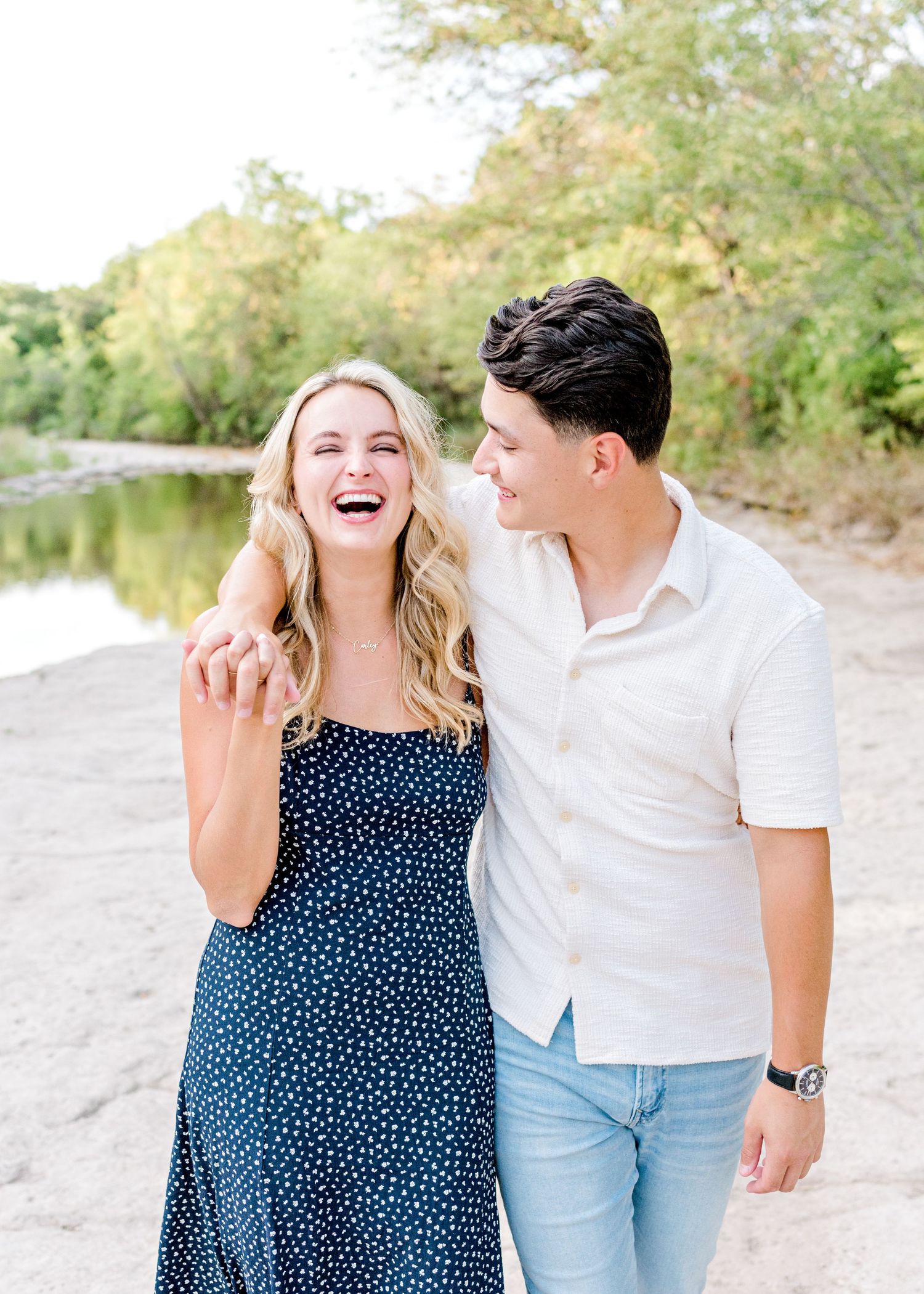 guy with his arm wrapped around girl as they hold hands and walk together in Austin. both laughing and smiling.