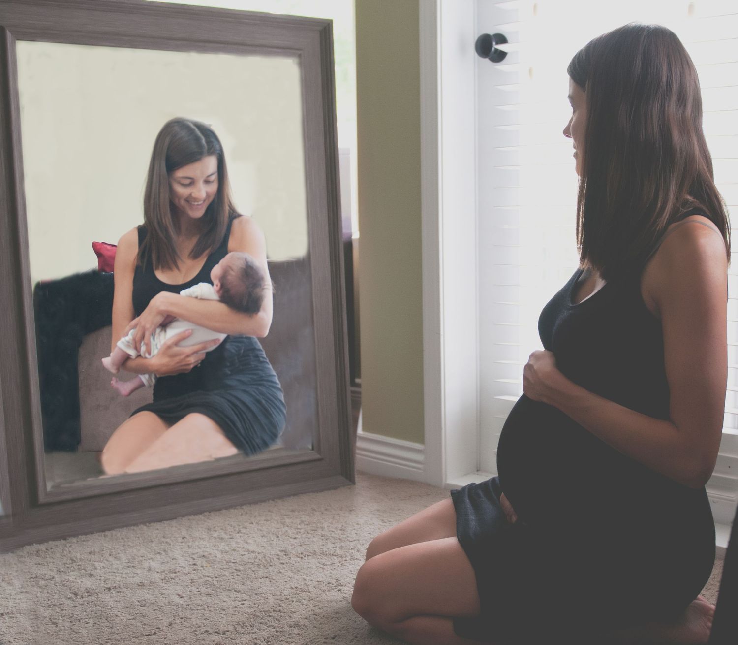 Reflection in mirror shows woman in black dress seated in home setting.