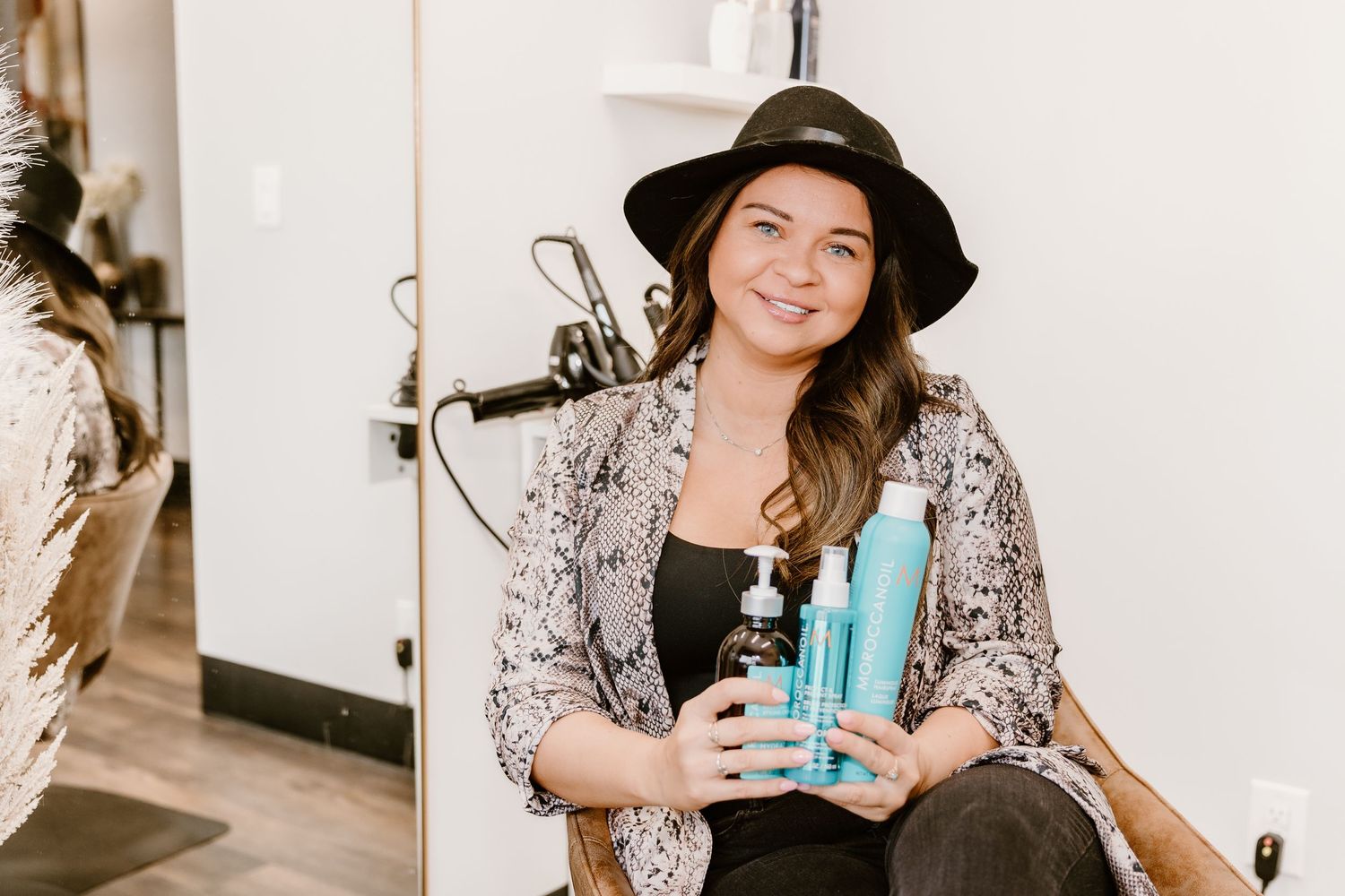Individual wearing wide-brim hat and sequin jacket holding turquoise water bottle.