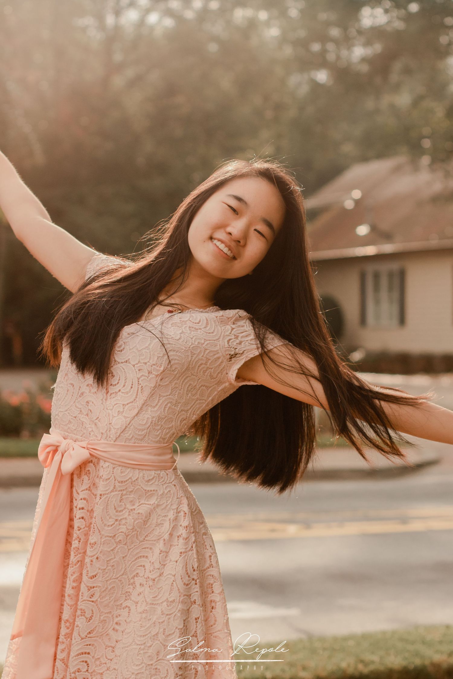 Joyful outdoor portrait in a peach lace dress during golden hour.