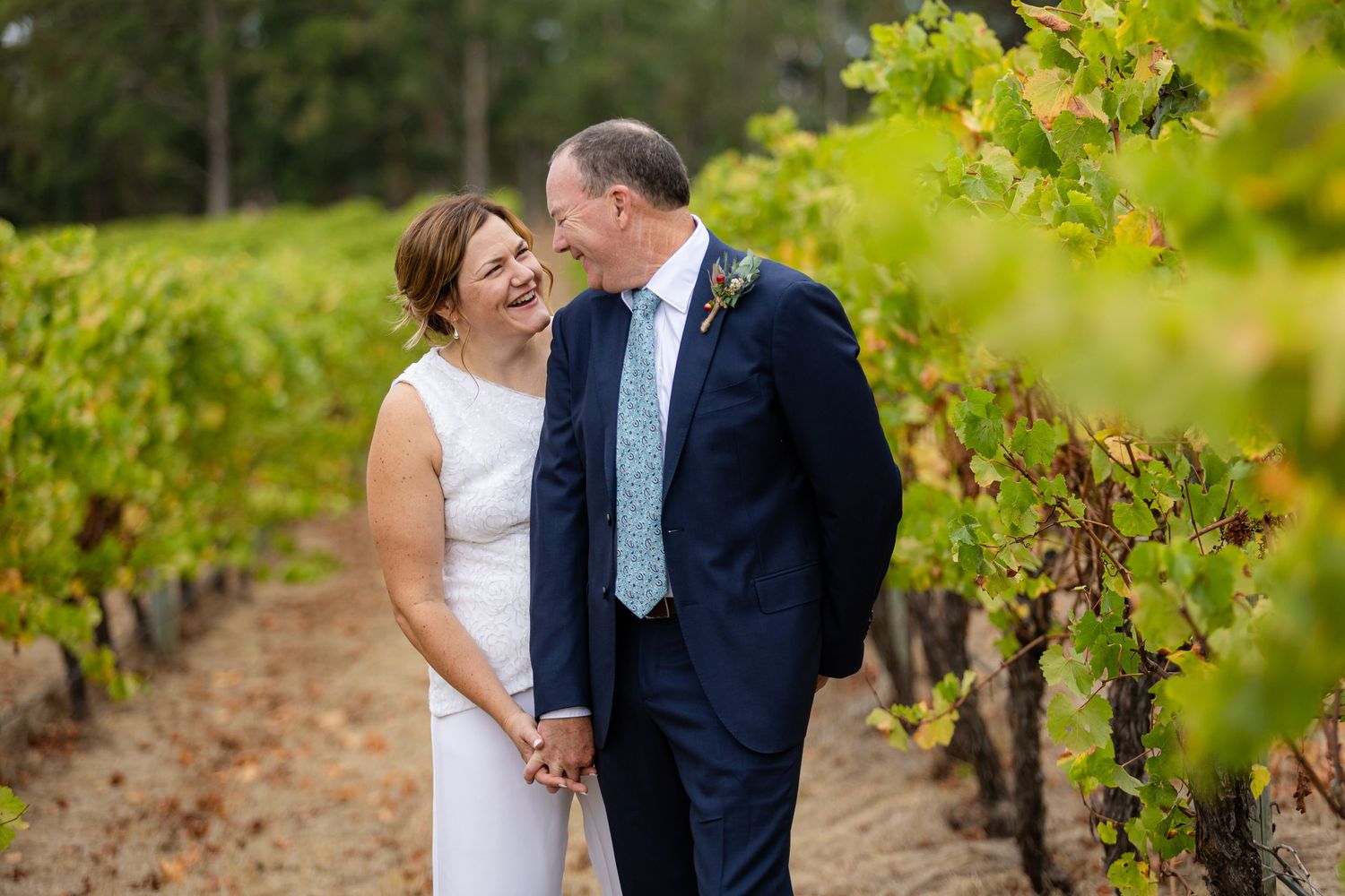 Happy couple sharing intimate moment among vineyard rows on their wedding day.