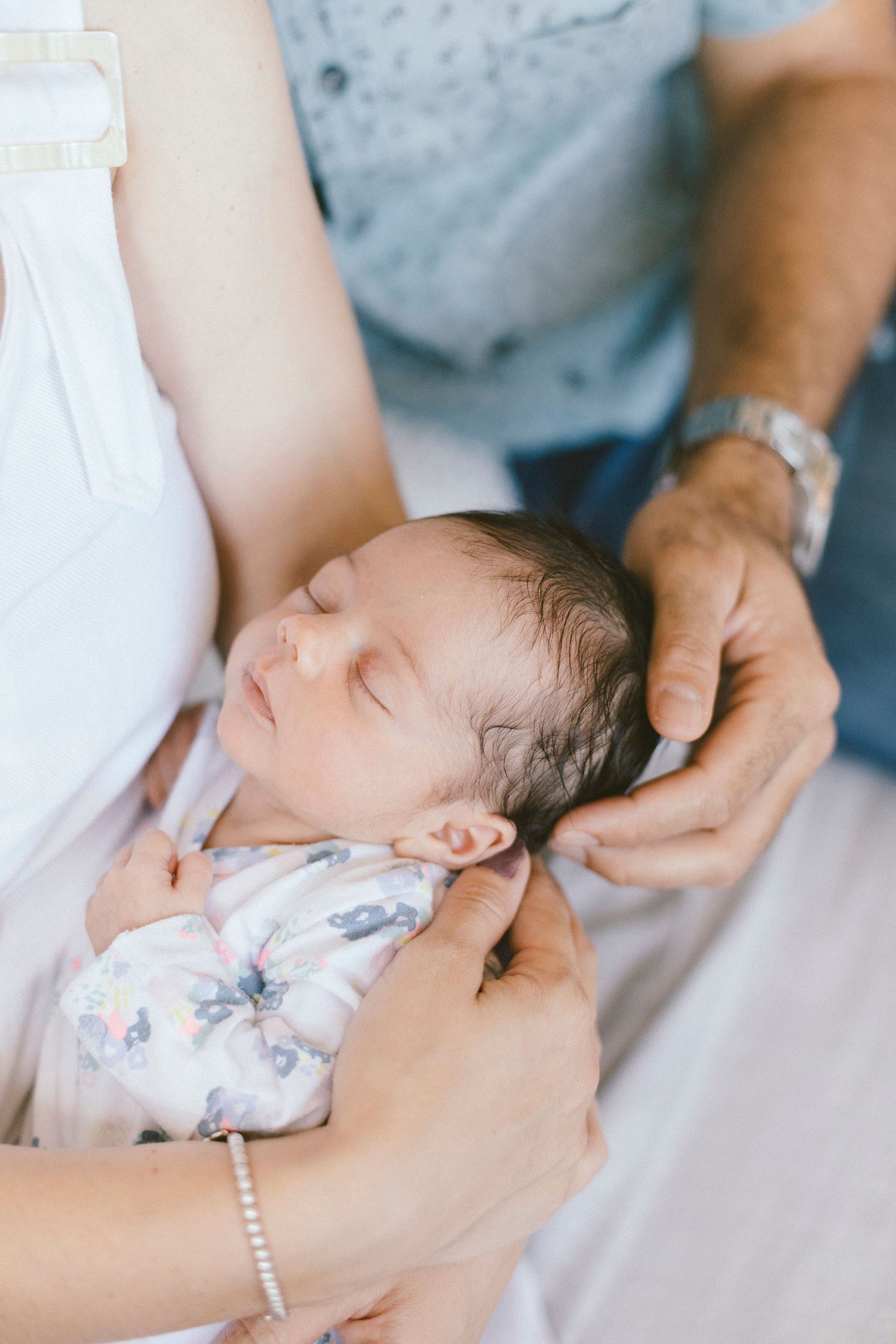 Close-up view of gentle hands supporting newborn baby's head.