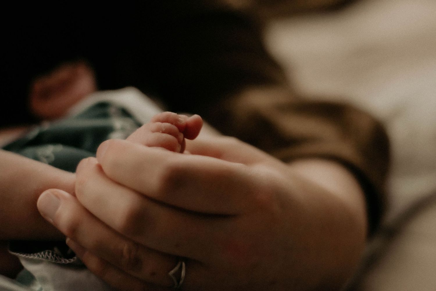 A close-up shot of tiny baby feet being held by gentle hands.