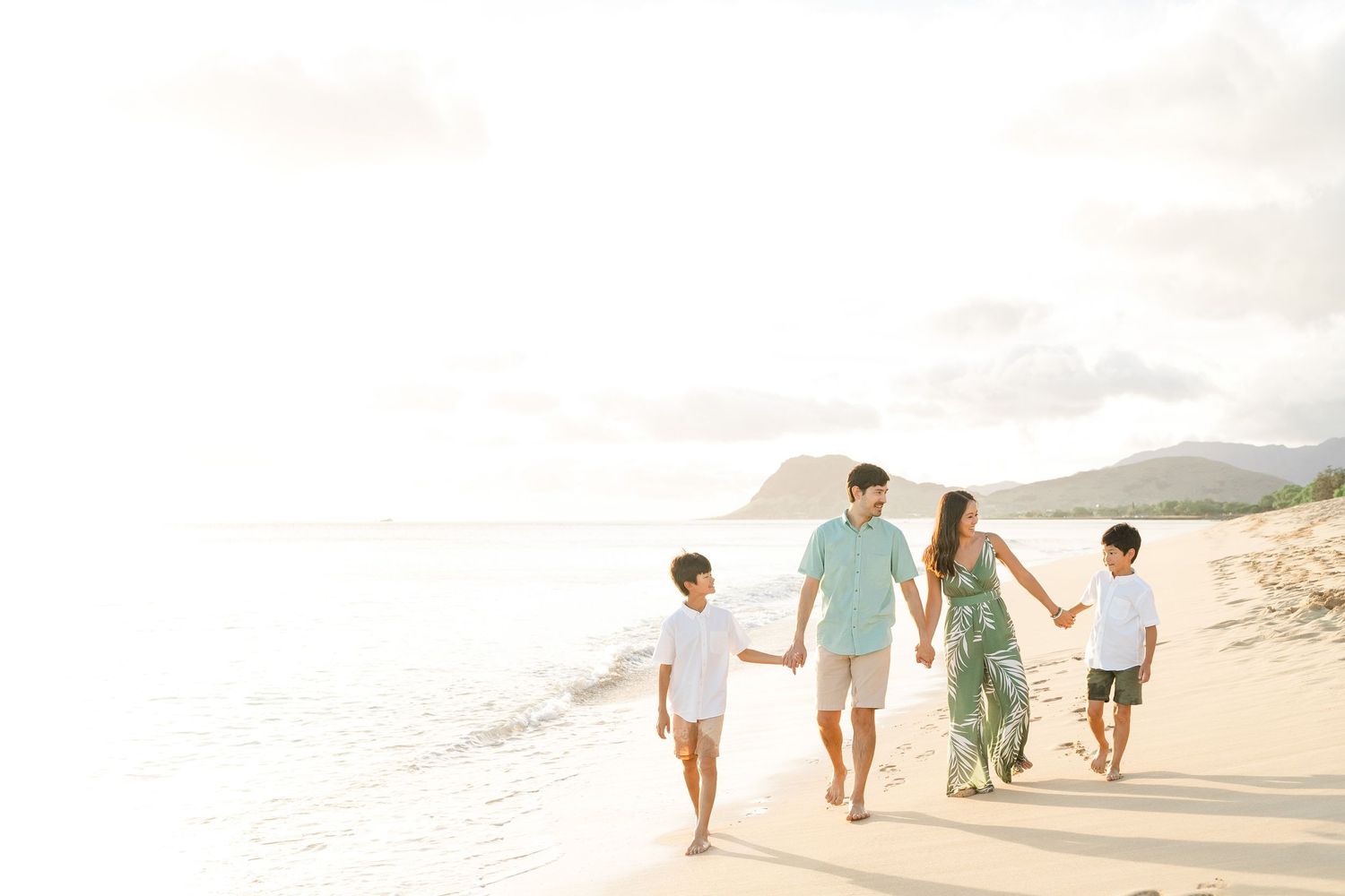 Family walking together along scenic beach shoreline at sunset.