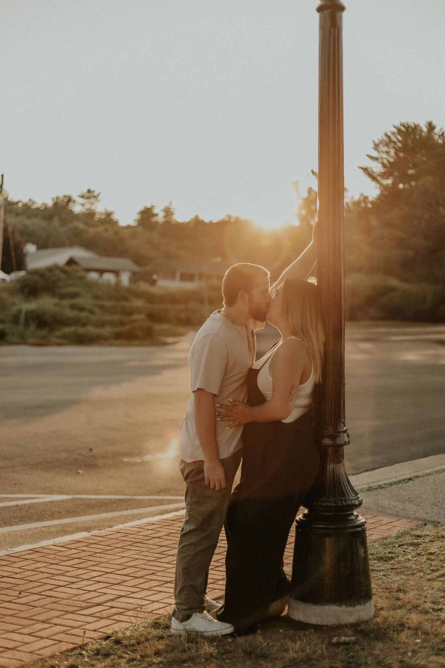 Couple shares an intimate moment by a lamp post during golden hour sunset.