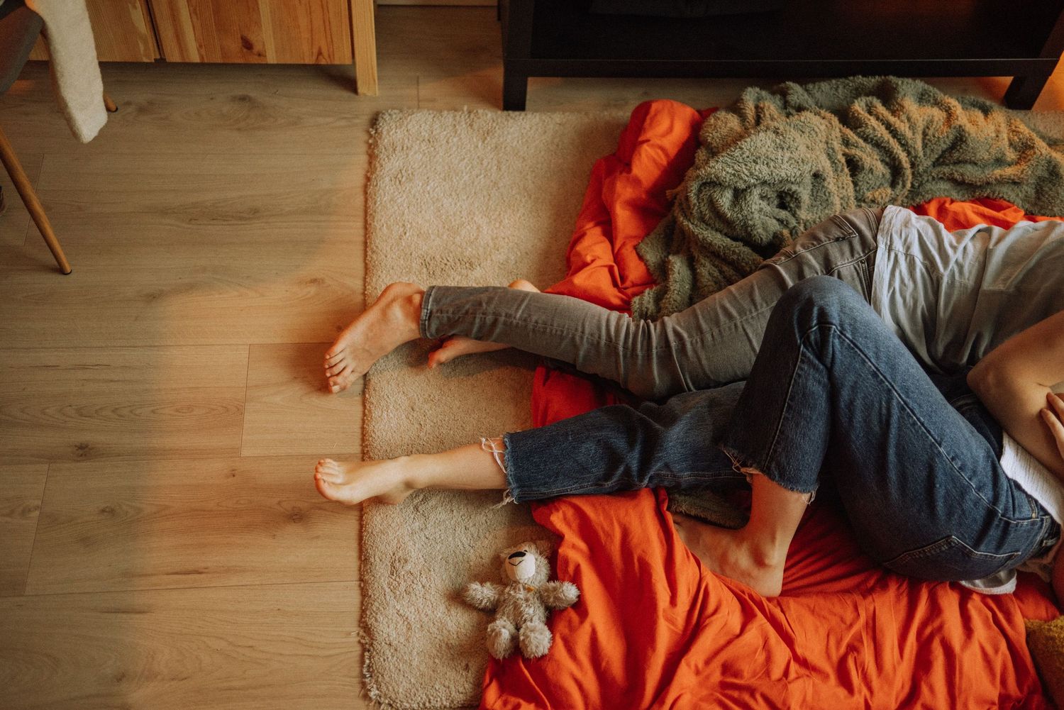 Couple relaxing together on an orange blanket in casual clothing.