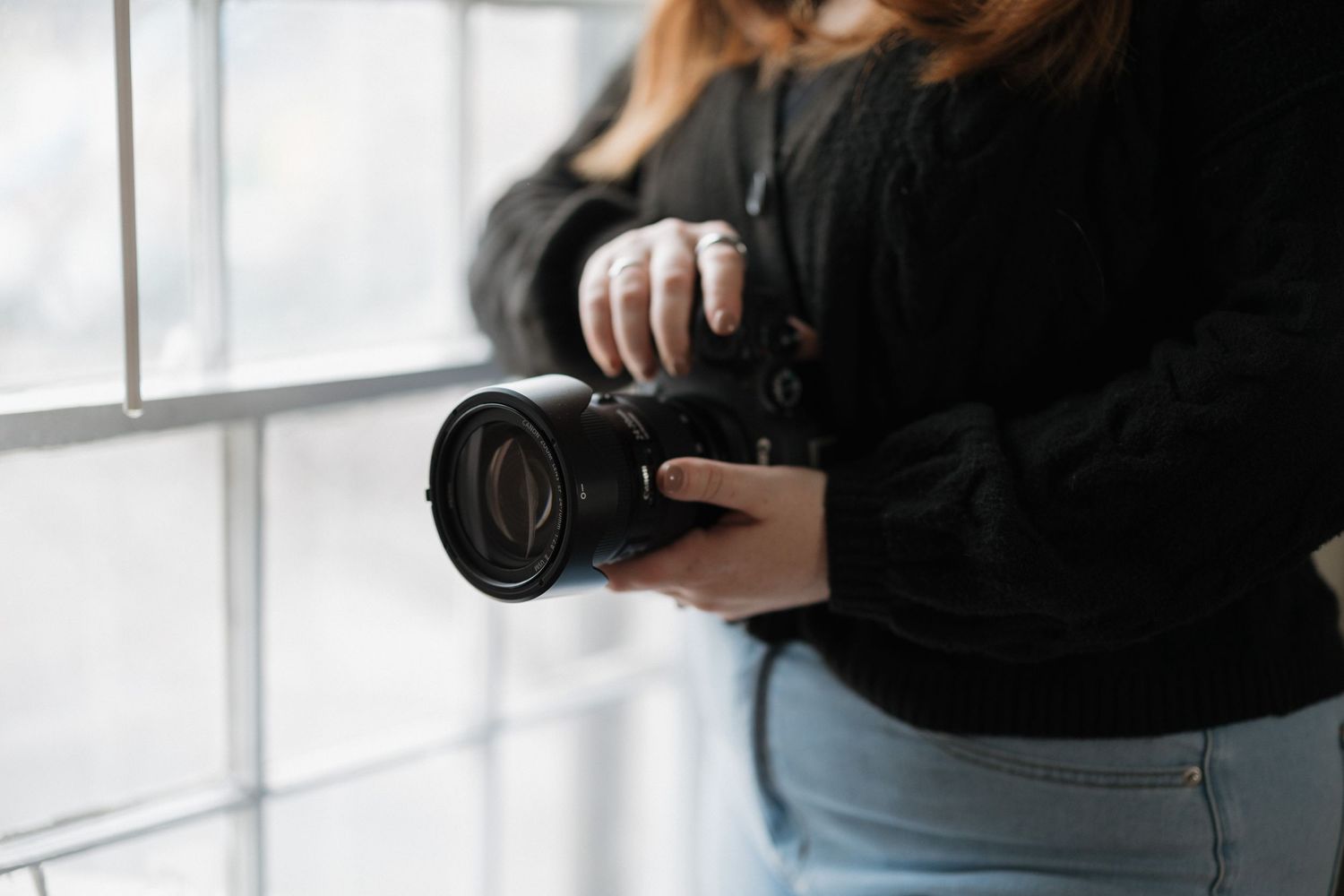 Photographer holding professional camera in natural window light.