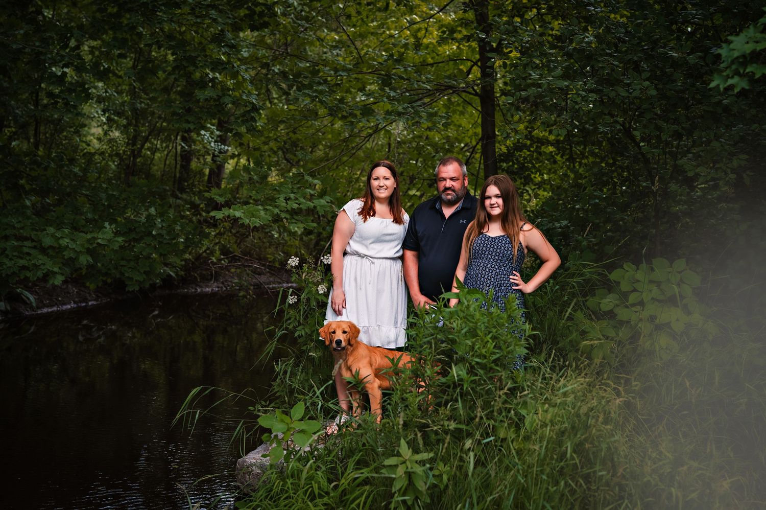 People standing together outdoors near green foliage during a summer photoshoot session.