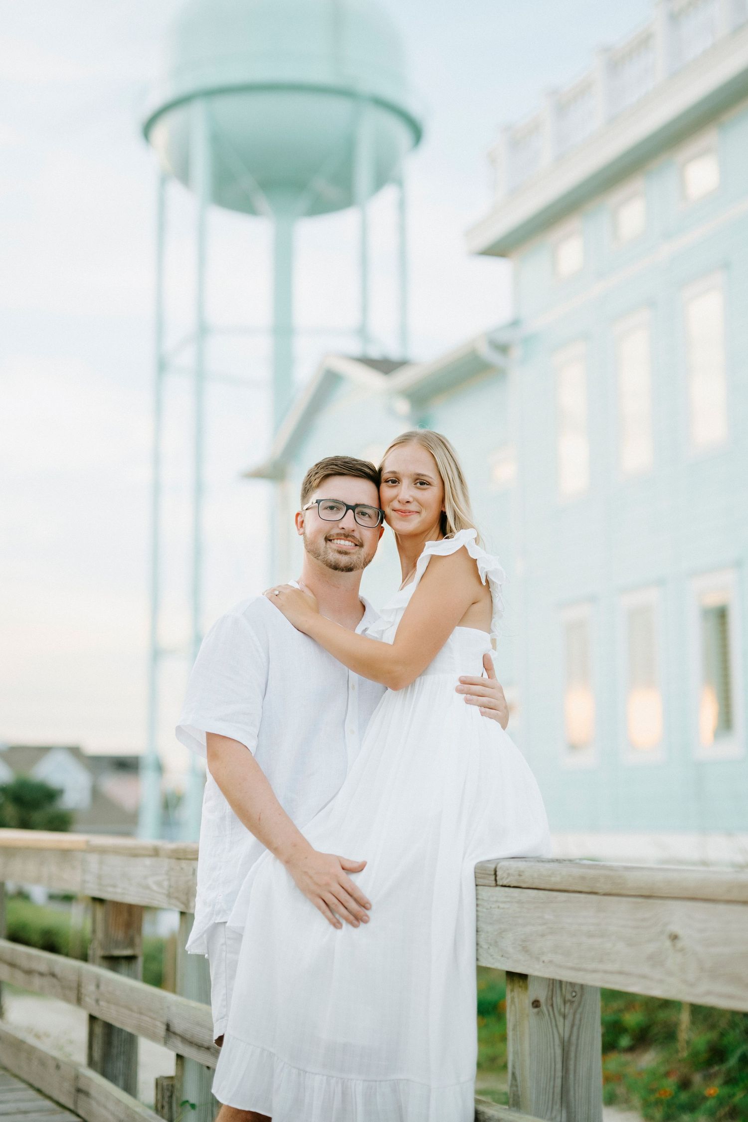 A romantic seaside photoshoot with white outfits against a mint green architectural backdrop.
