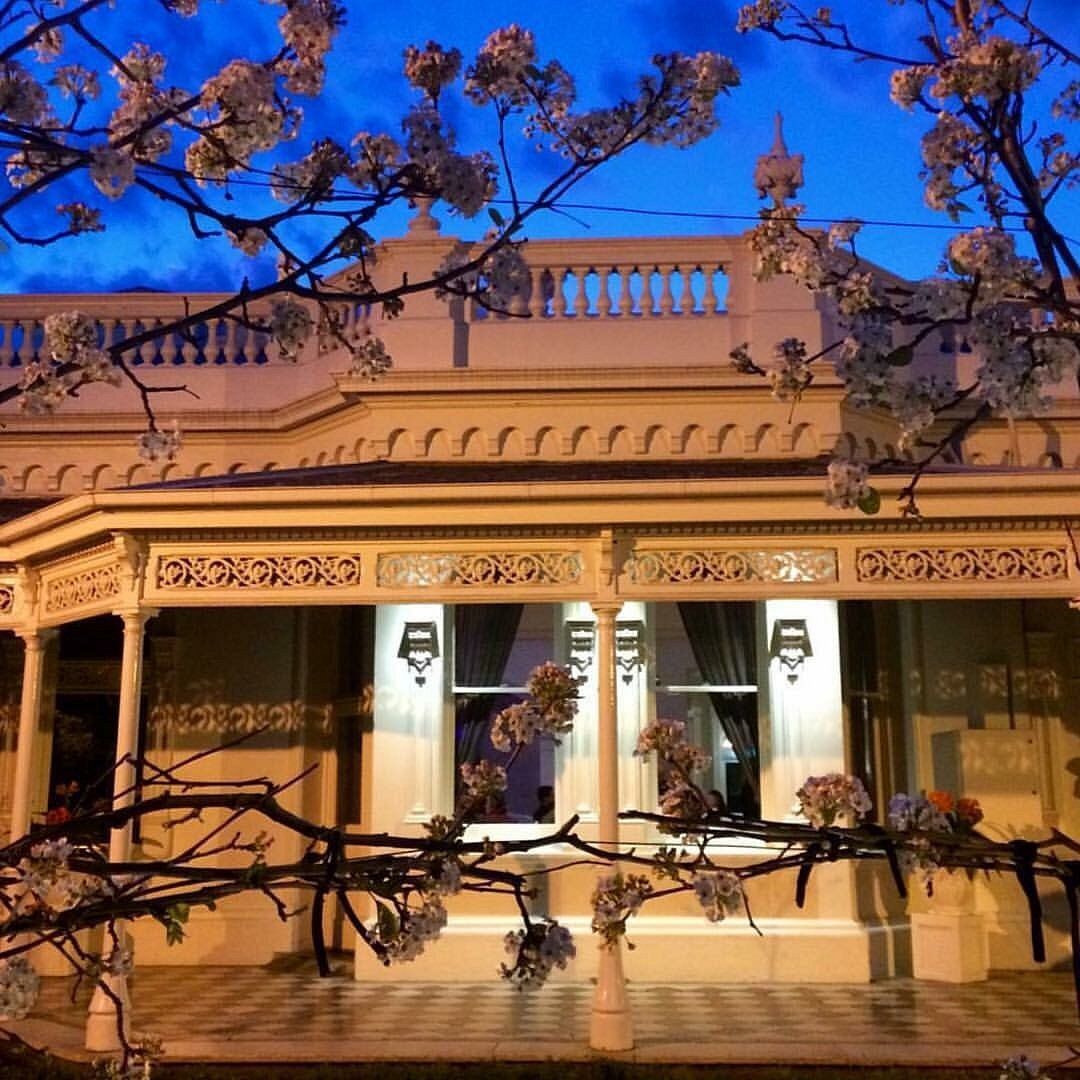 White colonial style building illuminated at night with ornate architectural details and glowing windows.