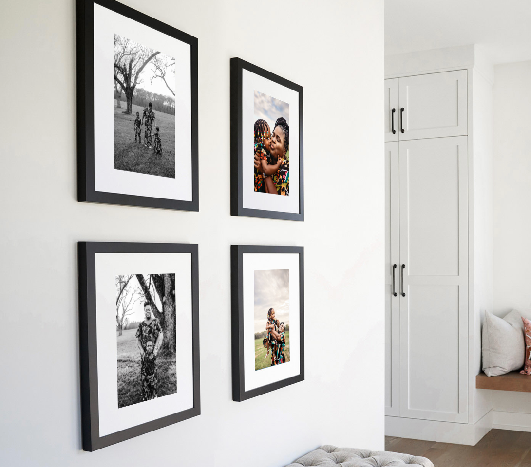 A minimalist gallery wall with framed artwork and photos arranged above a white sideboard with decorative items.