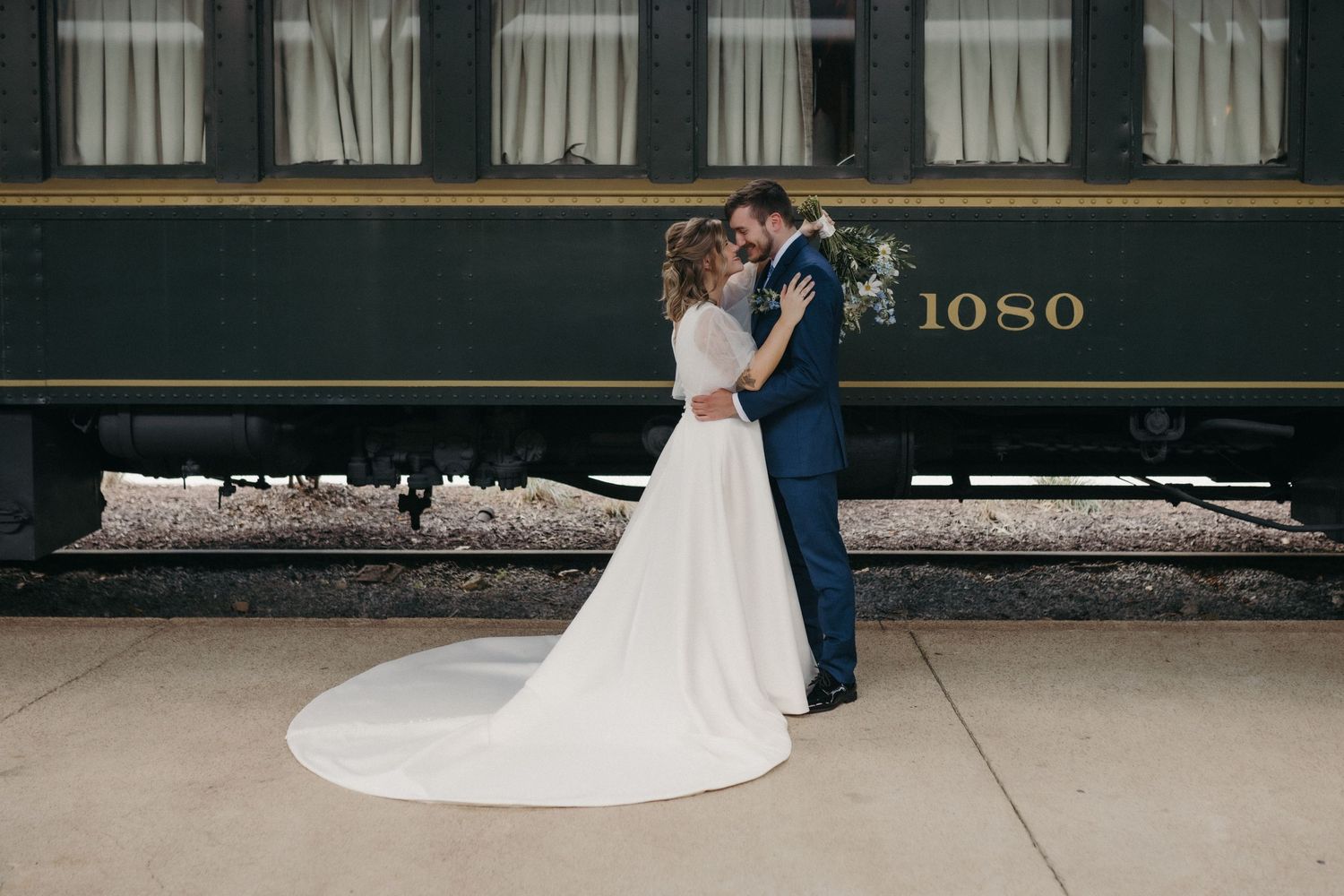 A couple in wedding attire dances together on a wooden floor during their first dance celebration.