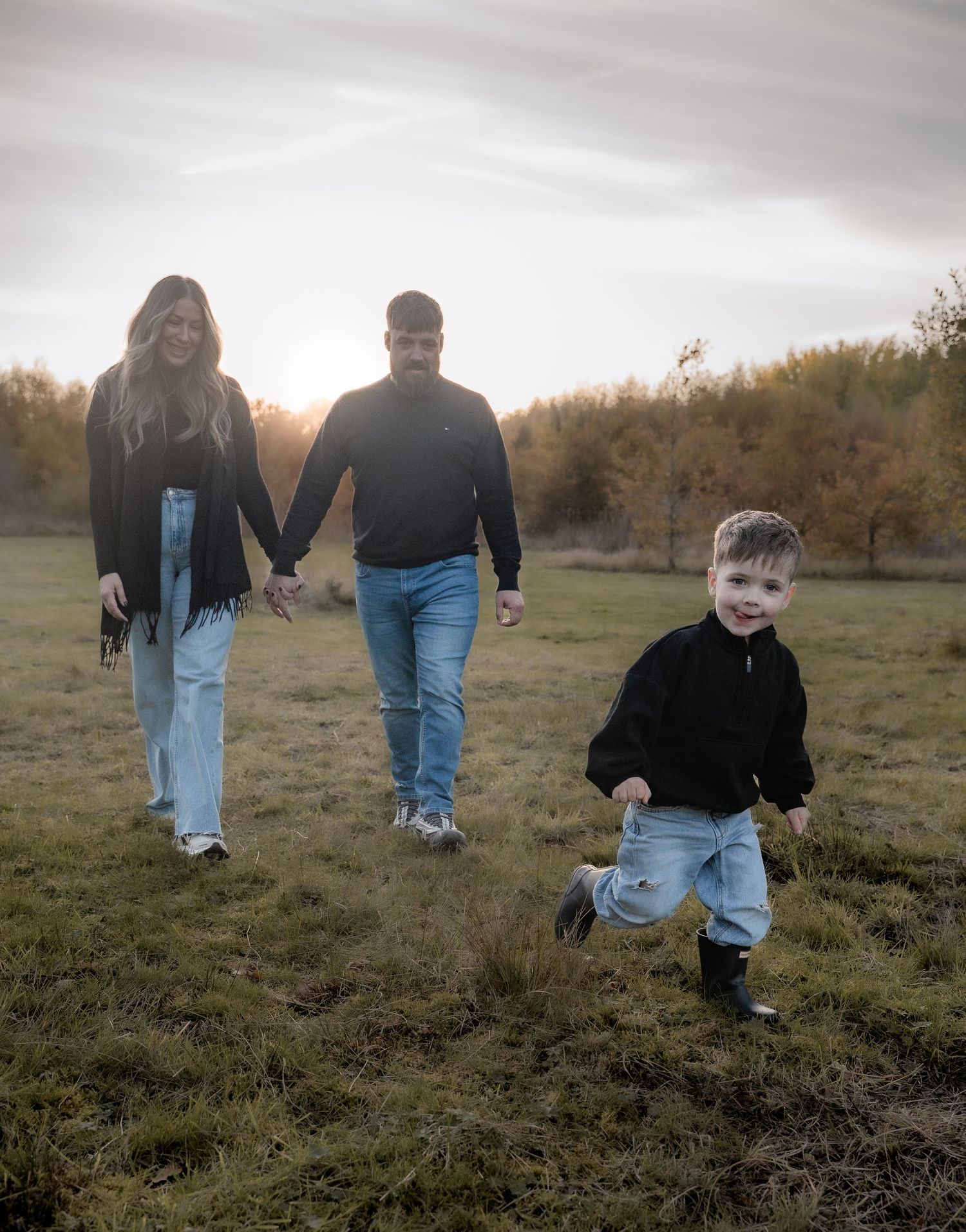 FAMILY WALKING THROUHG A FIELD IN AUTUMN DURING GOLDEN HOUR